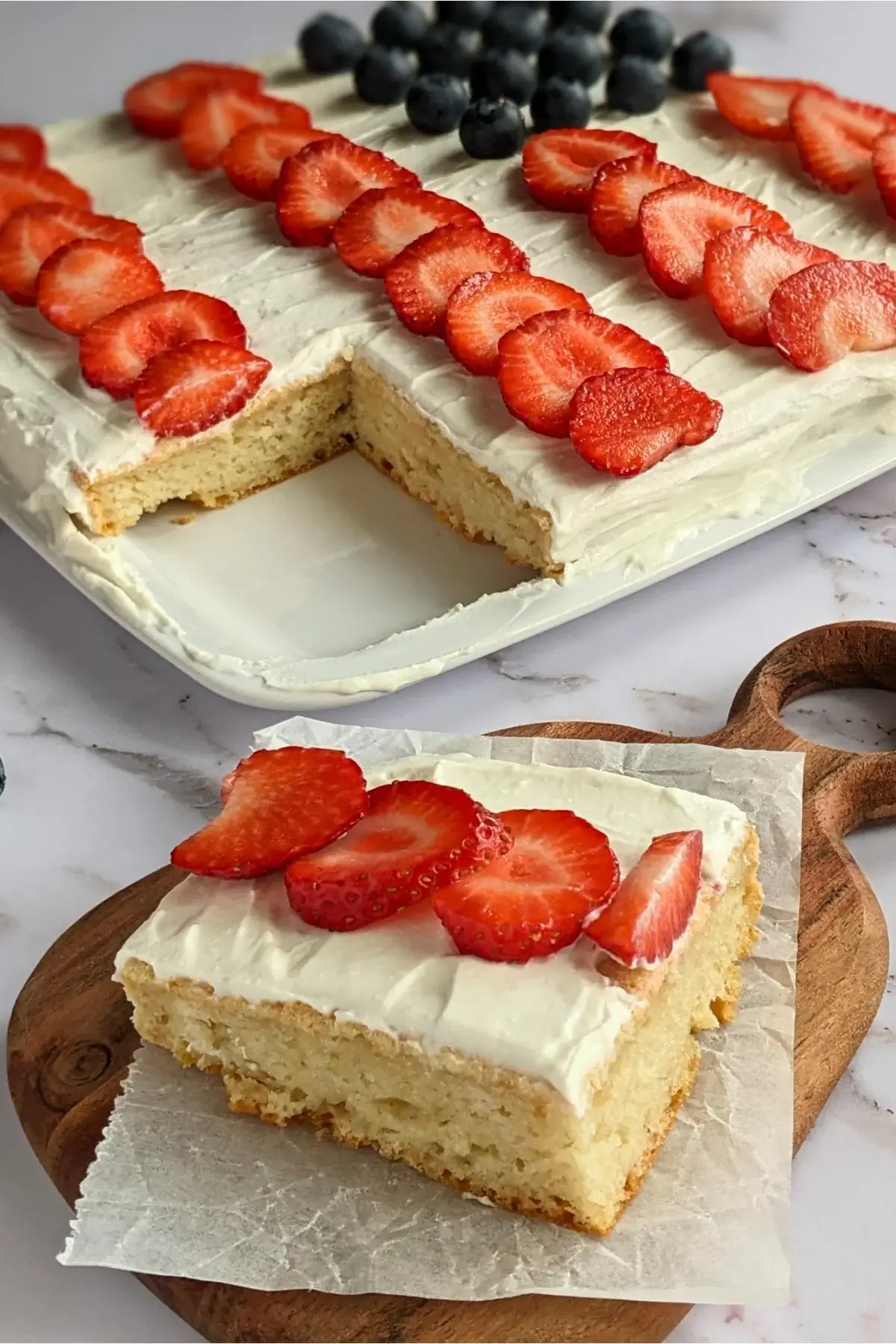 Sheet pan pancake decorated with blueberries and strawberries in the shape of an American flag, ideal for 4th of July celebrations.
