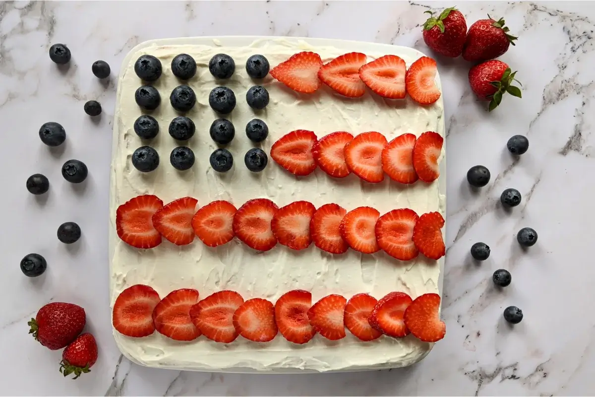 Sheet pan pancake decorated with blueberries and strawberries in the shape of an American flag, ideal for 4th of July celebrations.