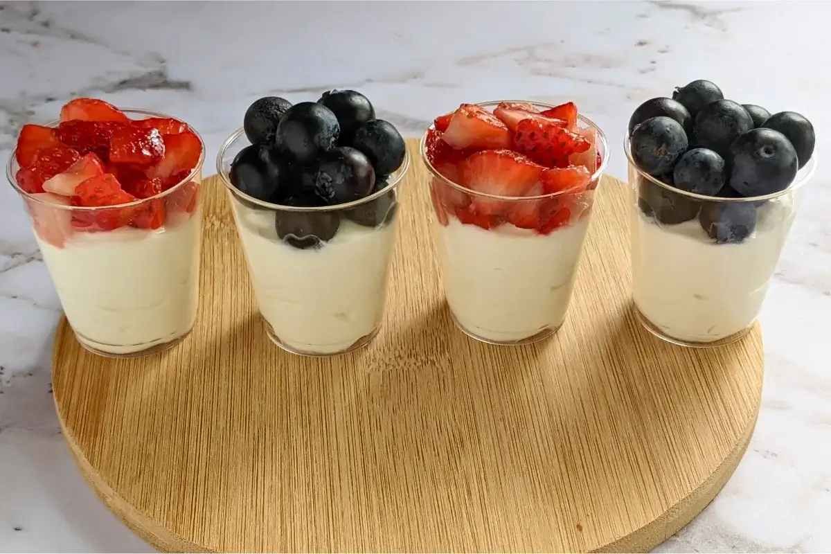 Individual dessert shooters with mascarpone and Greek yogurt mix, topped with either strawberries or blueberries.