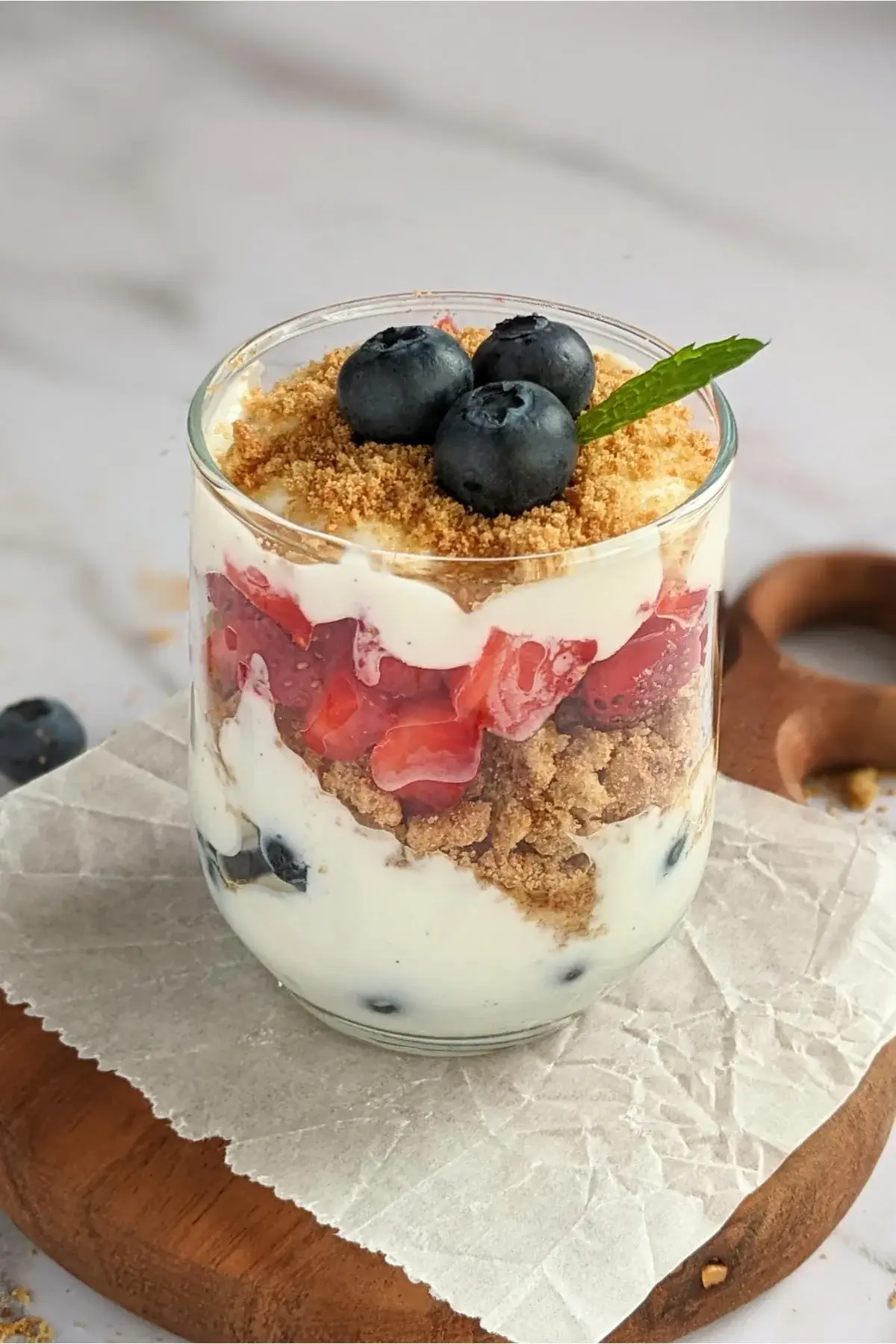 Parfait cups filled with layers of Greek yogurt, oat cookies, strawberries, blueberries, and a drizzle of honey.
