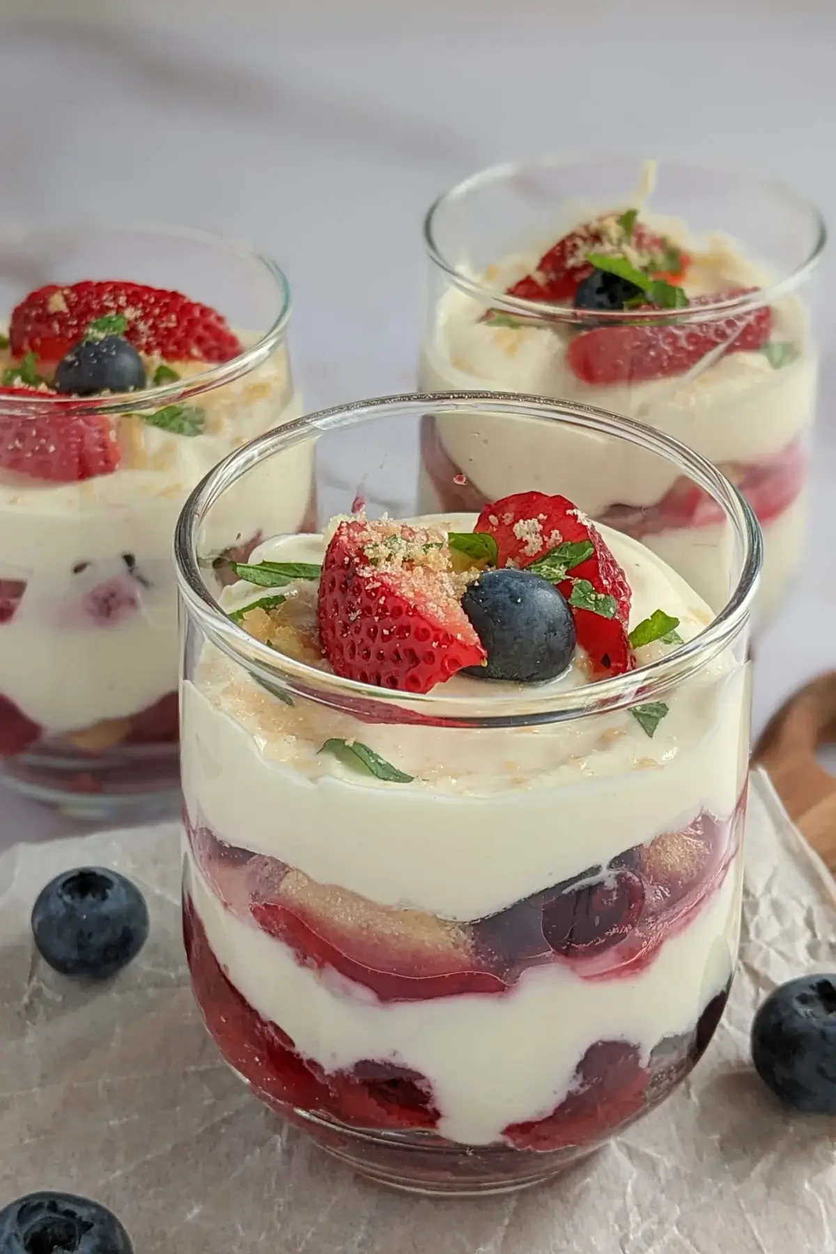 Red, white & blue berry tiramisu Cups with layers of mascarpone, Greek yogurt, and fresh berries in clear cups.