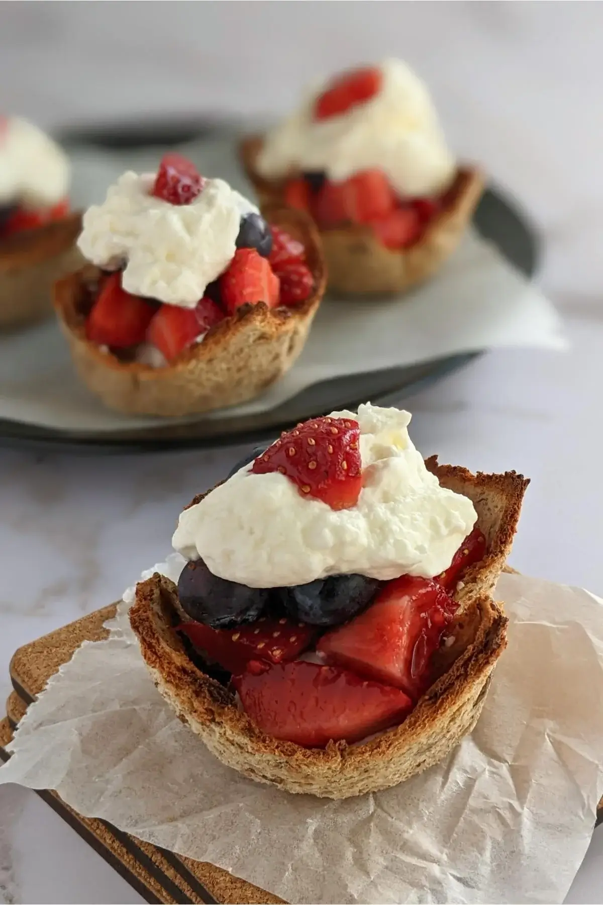 Crispy bread cups filled with fresh berries and topped with a swirl of whipped cream for a light dessert bite.