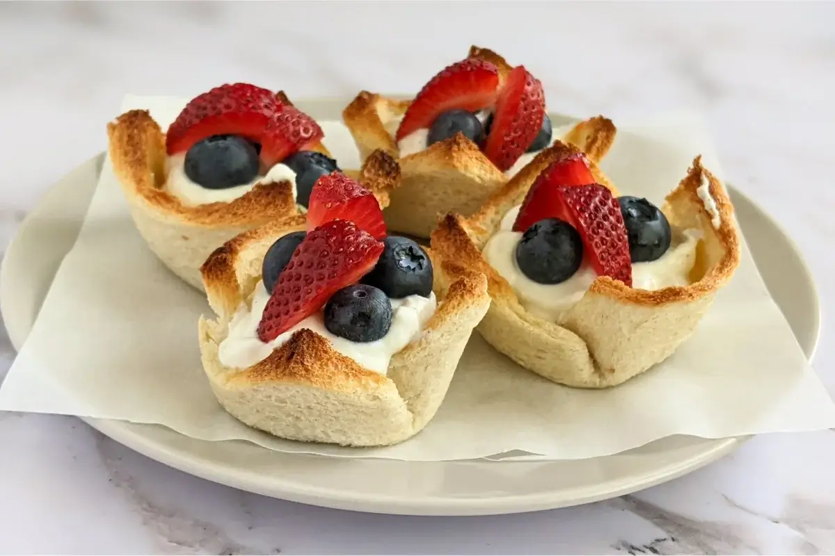White bread cups filled with sweet whipped ricotta and topped with fresh strawberries and blueberries for a healthy summer treat.