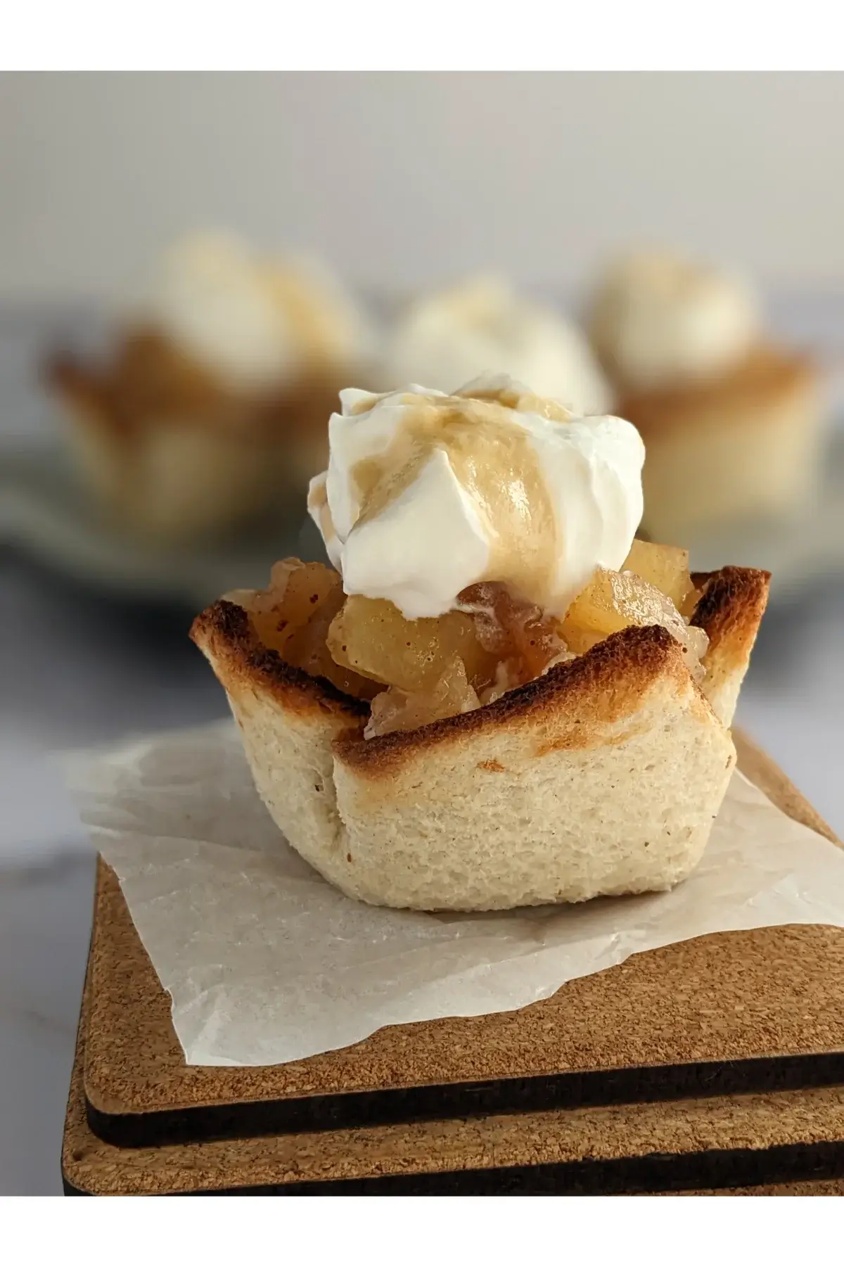 White bread cups filled with applesauce and whipped cream arranged on a serving plate.