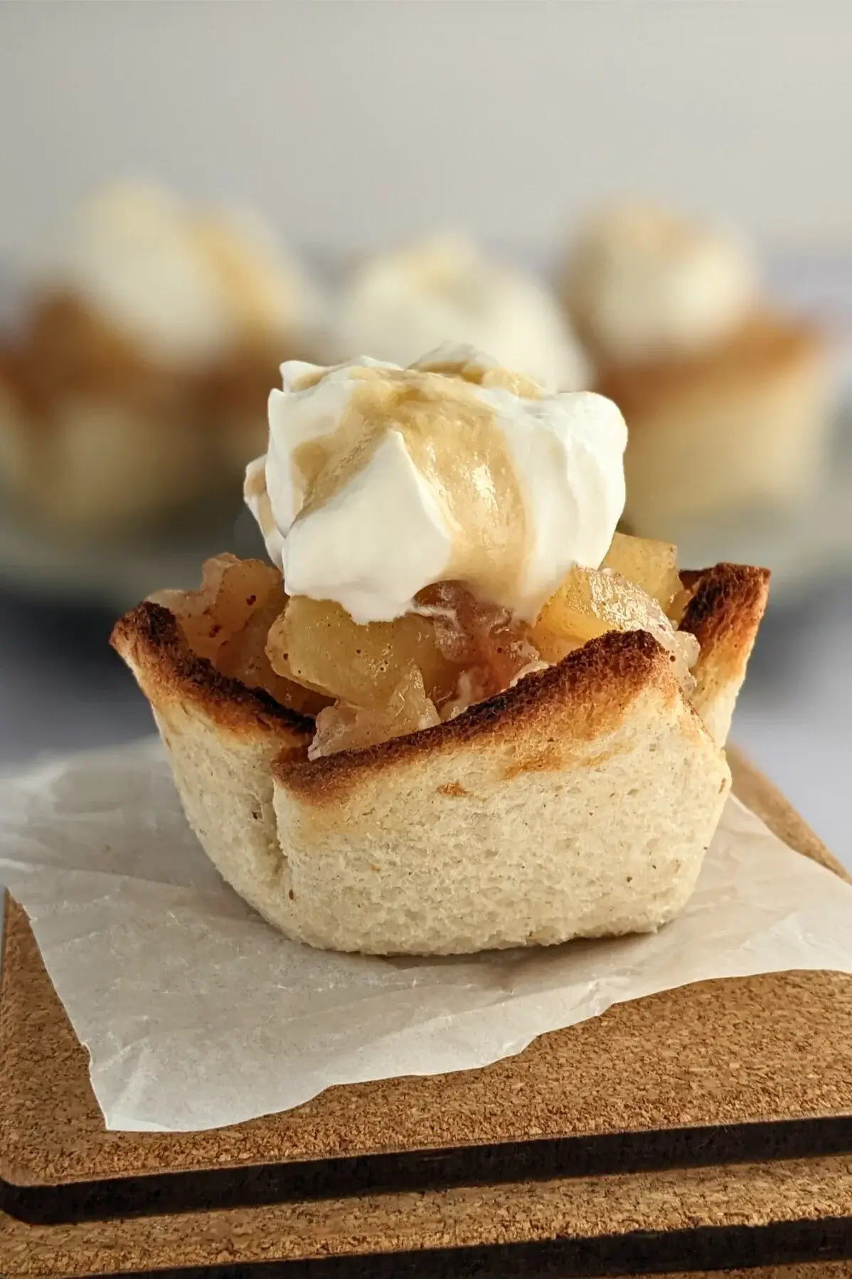 White bread cups filled with applesauce and whipped cream arranged on a serving plate.