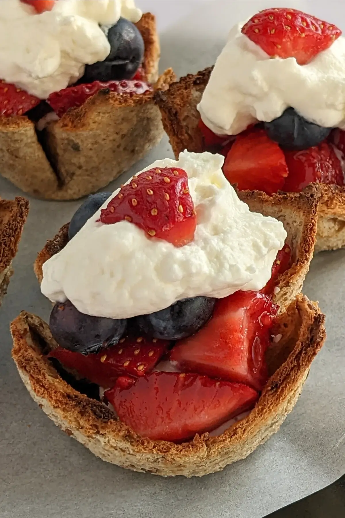 Wholemeal bread cups filled with berry compote and topped with whipped cream.