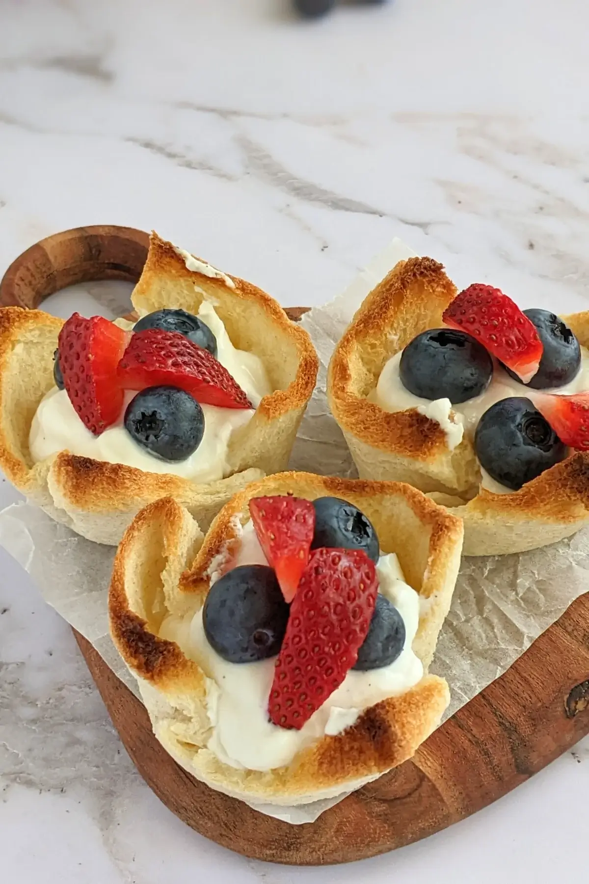 White bread cups with sweet ricotta filling and fresh strawberries and blueberries.
