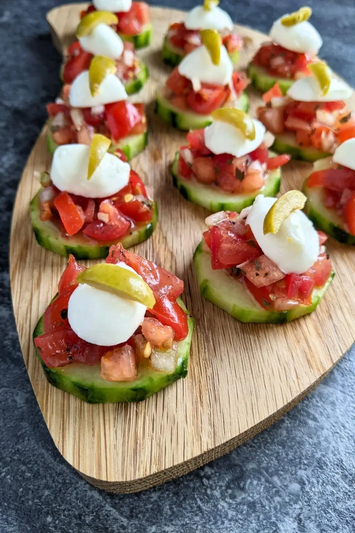 Crisp cucumber slices topped with fresh tomato bruschetta mix and herbs for a refreshing bite-sized snack.