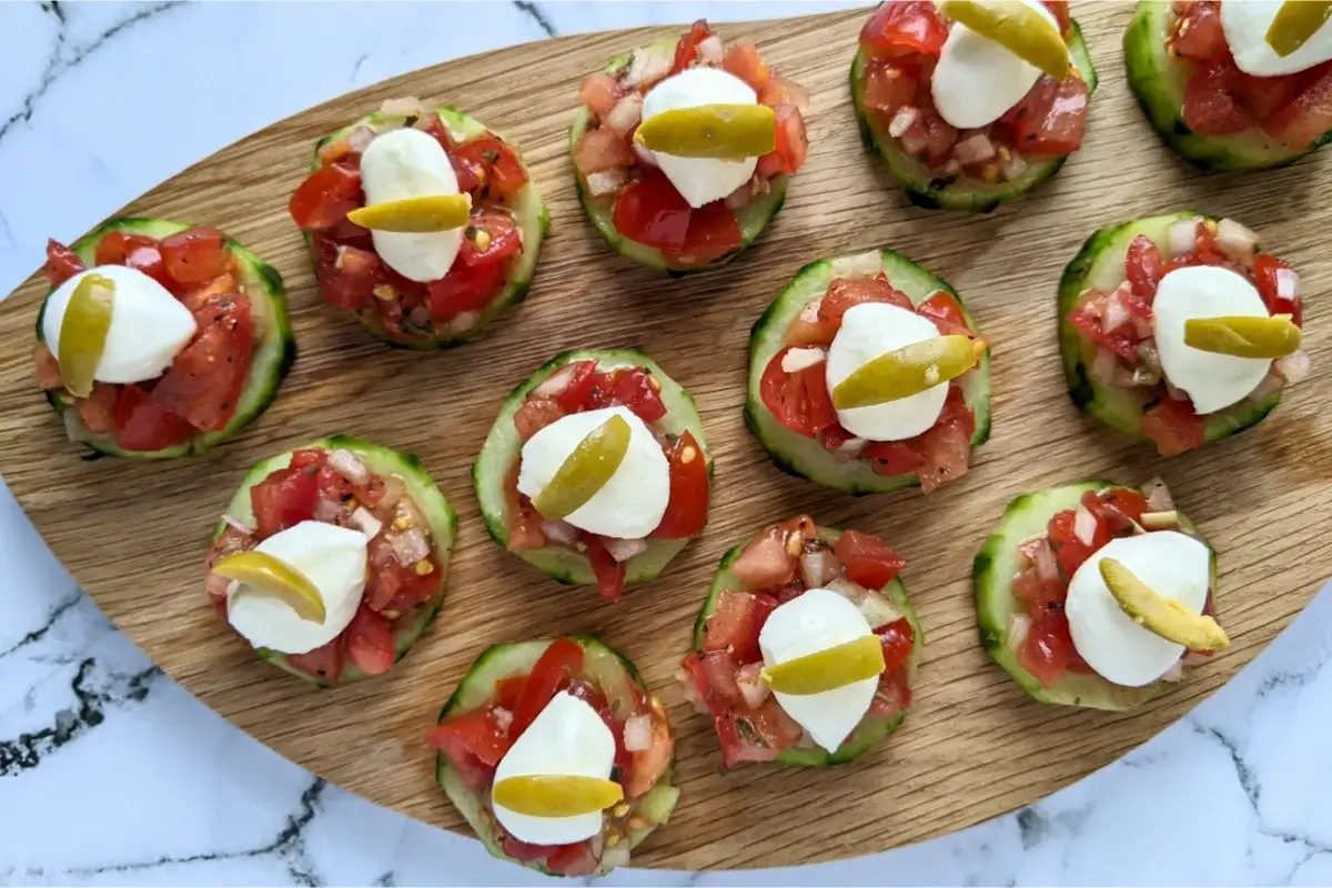 Crisp cucumber slices topped with fresh tomato bruschetta mix and herbs for a refreshing bite-sized snack.