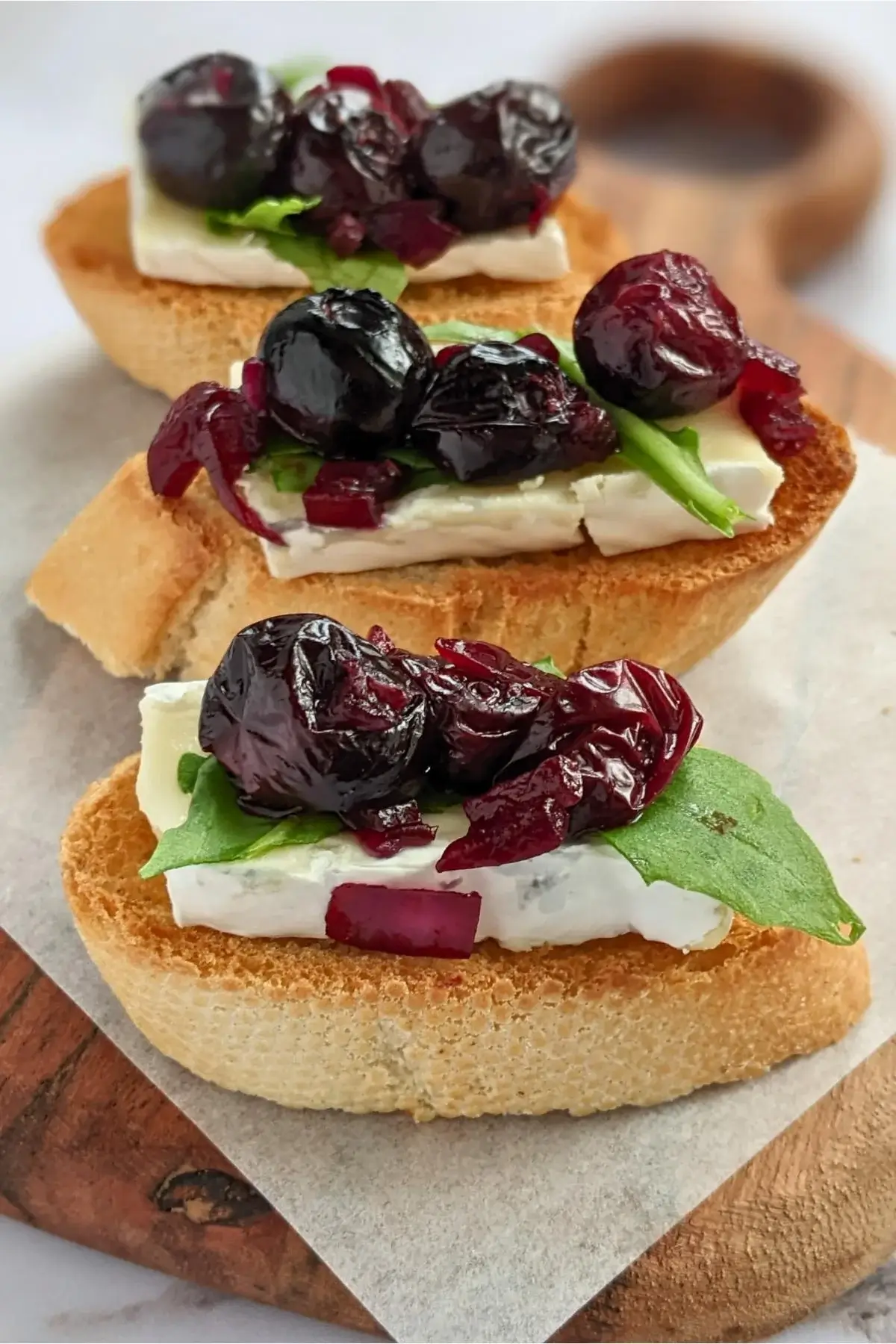 Toasted crostini with warm blueberries, creamy brie, and peppery arugula for a sweet-savory appetizer.