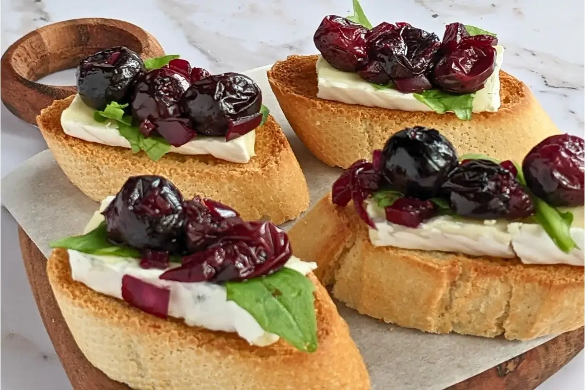 Toasted crostini with warm blueberries, creamy brie, and peppery arugula for a sweet-savory appetizer.