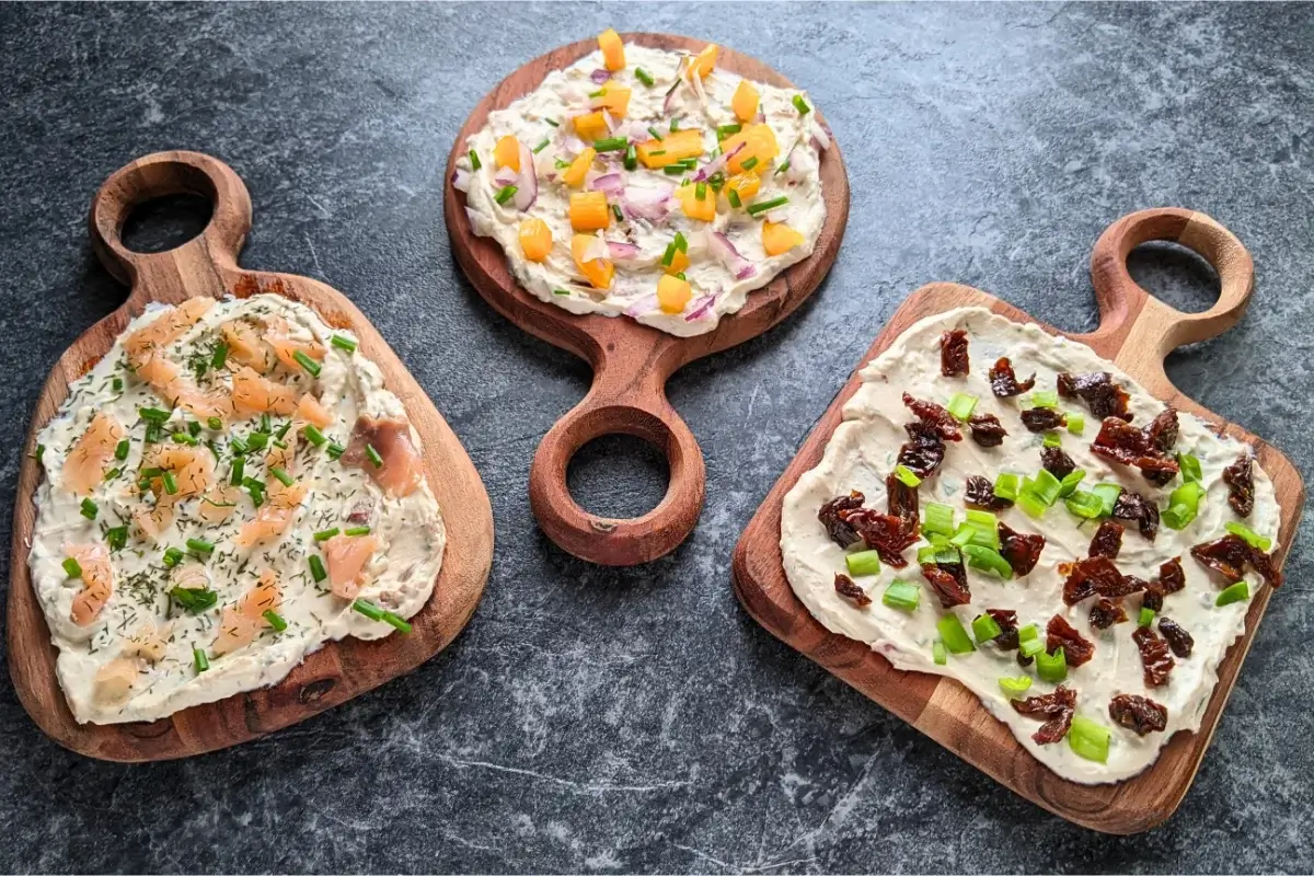Feta cheese spread boards with a mix of savory toppings like red onion and yellow capsicum, sundried tomatoes and green onion, and smoked salmon and chives.