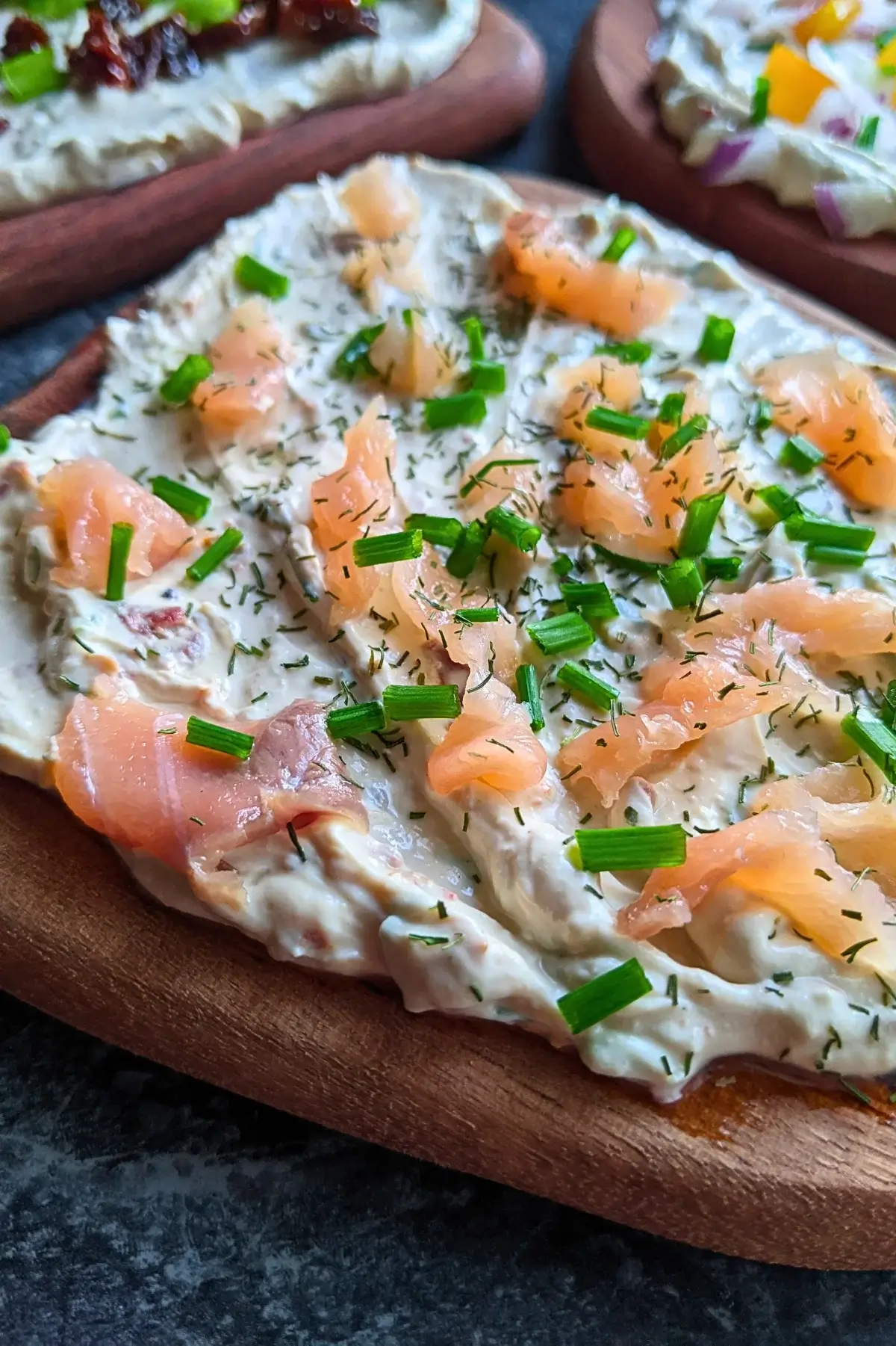 Trio of flavored feta boards topped with smoked salmon, sun-dried tomatoes, and colorful veggies on creamy feta dip.