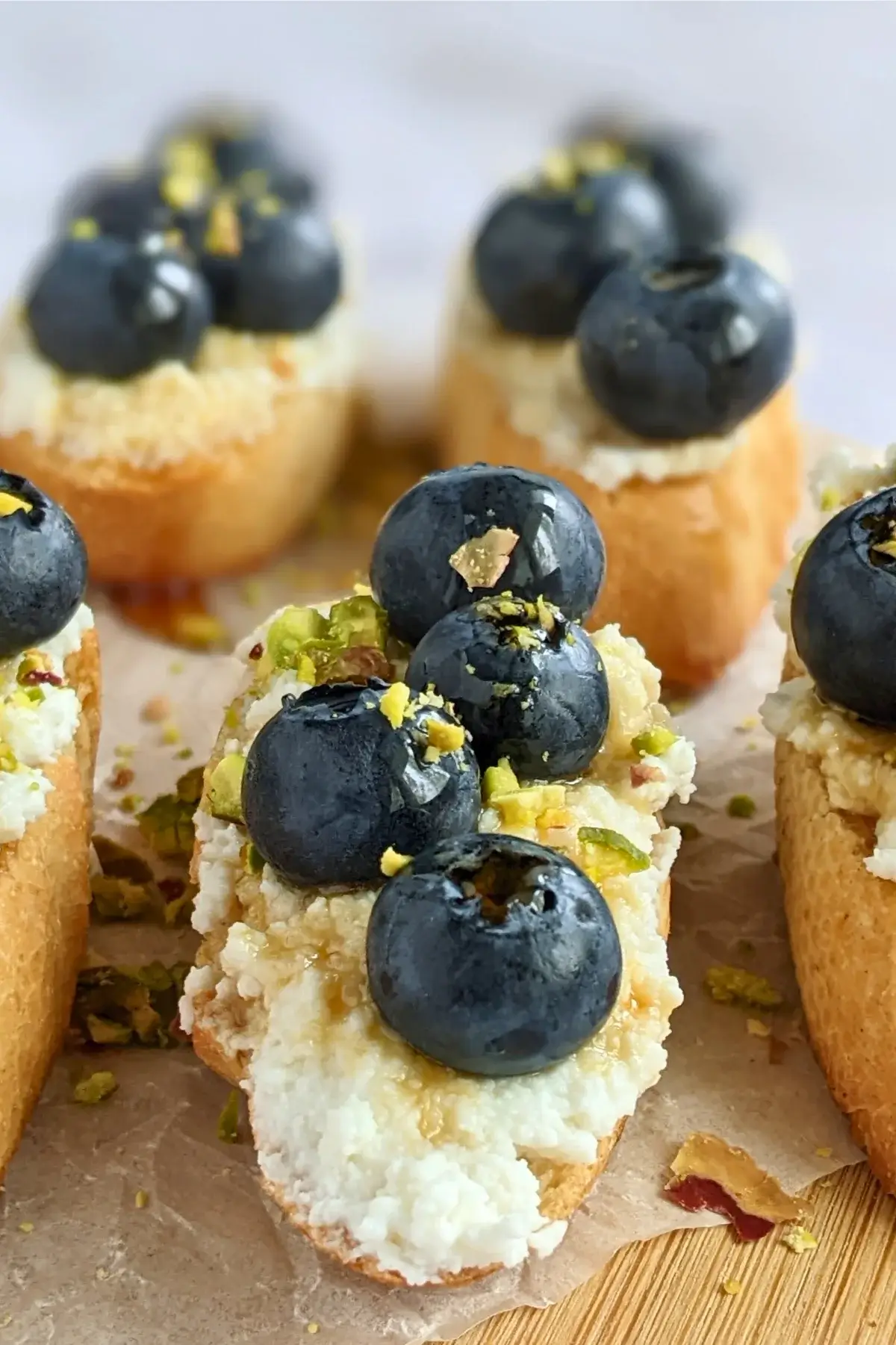 Crostini with creamy sweet ricotta and fresh blueberries arranged on a serving plate.