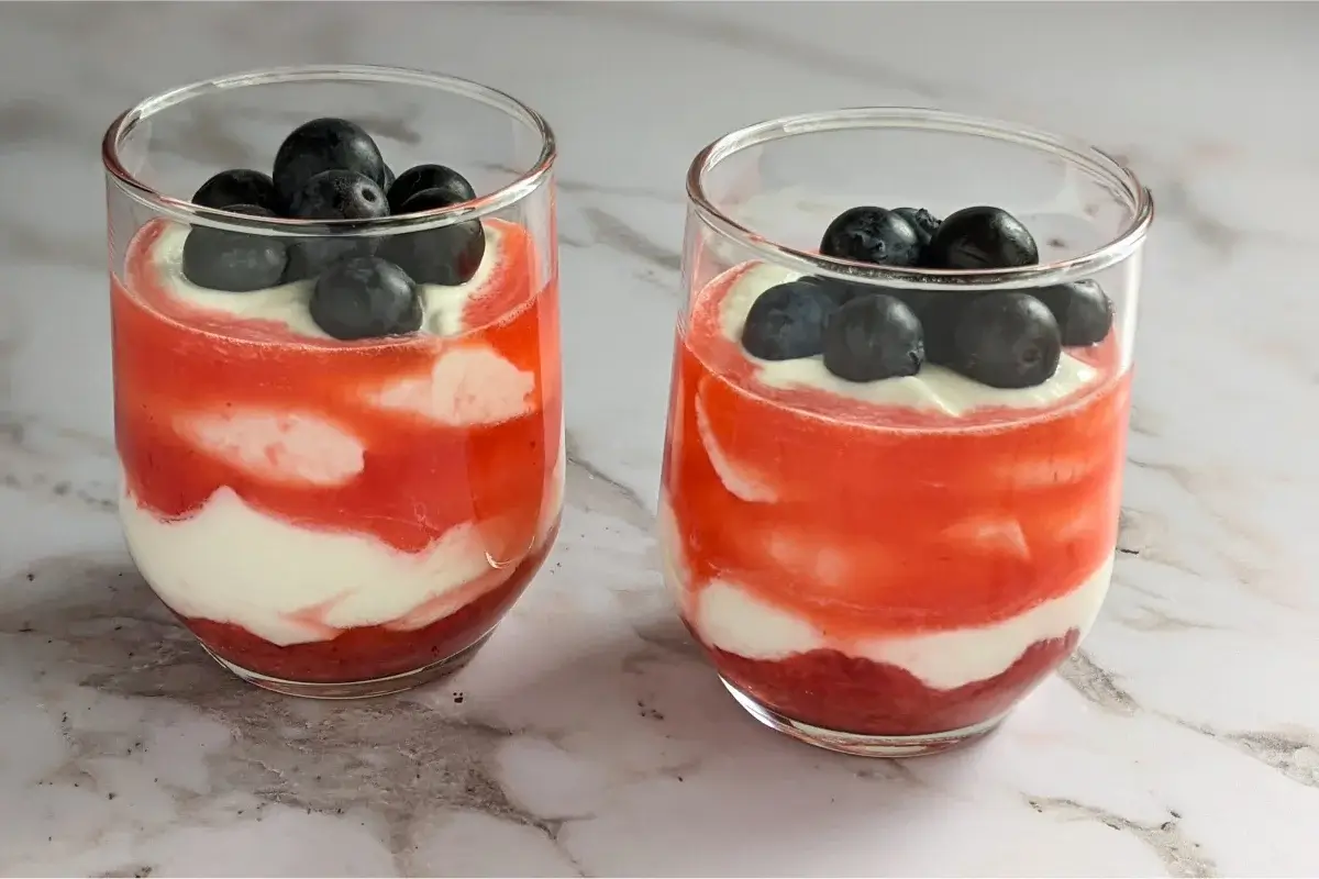 Layered berry fool dessert made with whipped cream, Greek yogurt, and a medley of fresh berries and berry syrup.