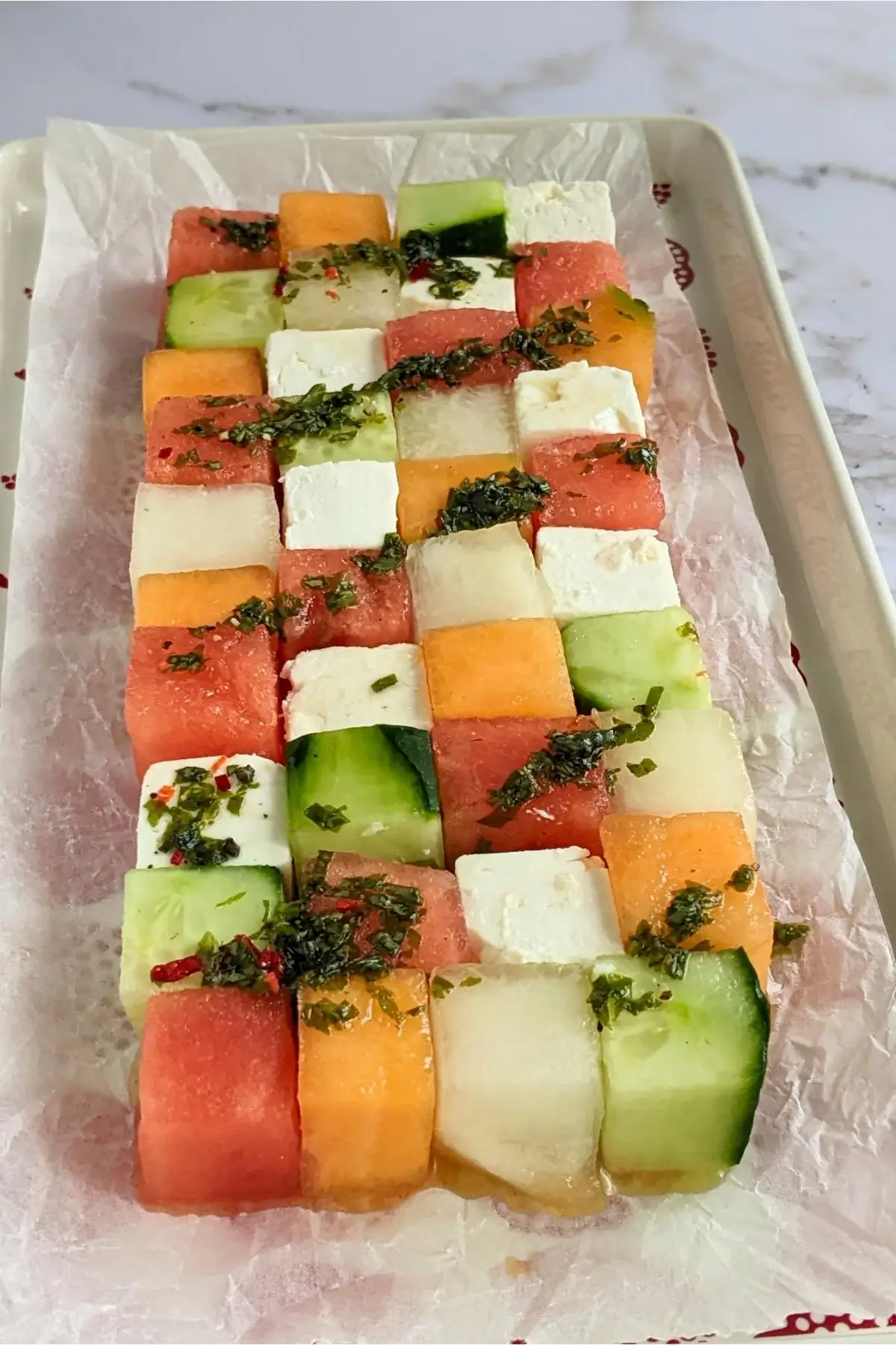 Cubed melon, cucumber, watermelon, and feta arranged like Tetris blocks for a fun and fresh summer salad.