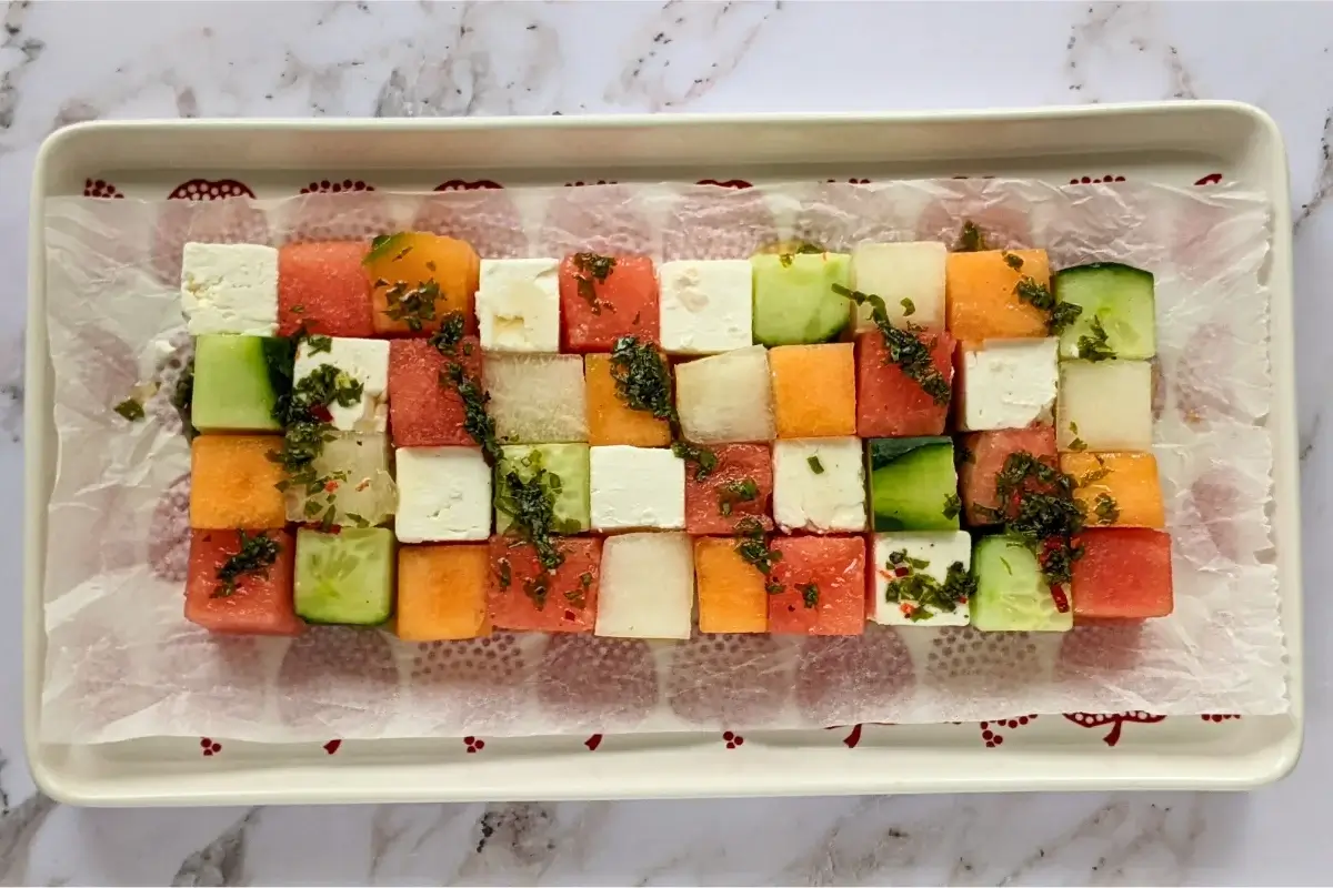 Cubed melon, cucumber, watermelon, and feta arranged like Tetris blocks for a fun and fresh summer salad.