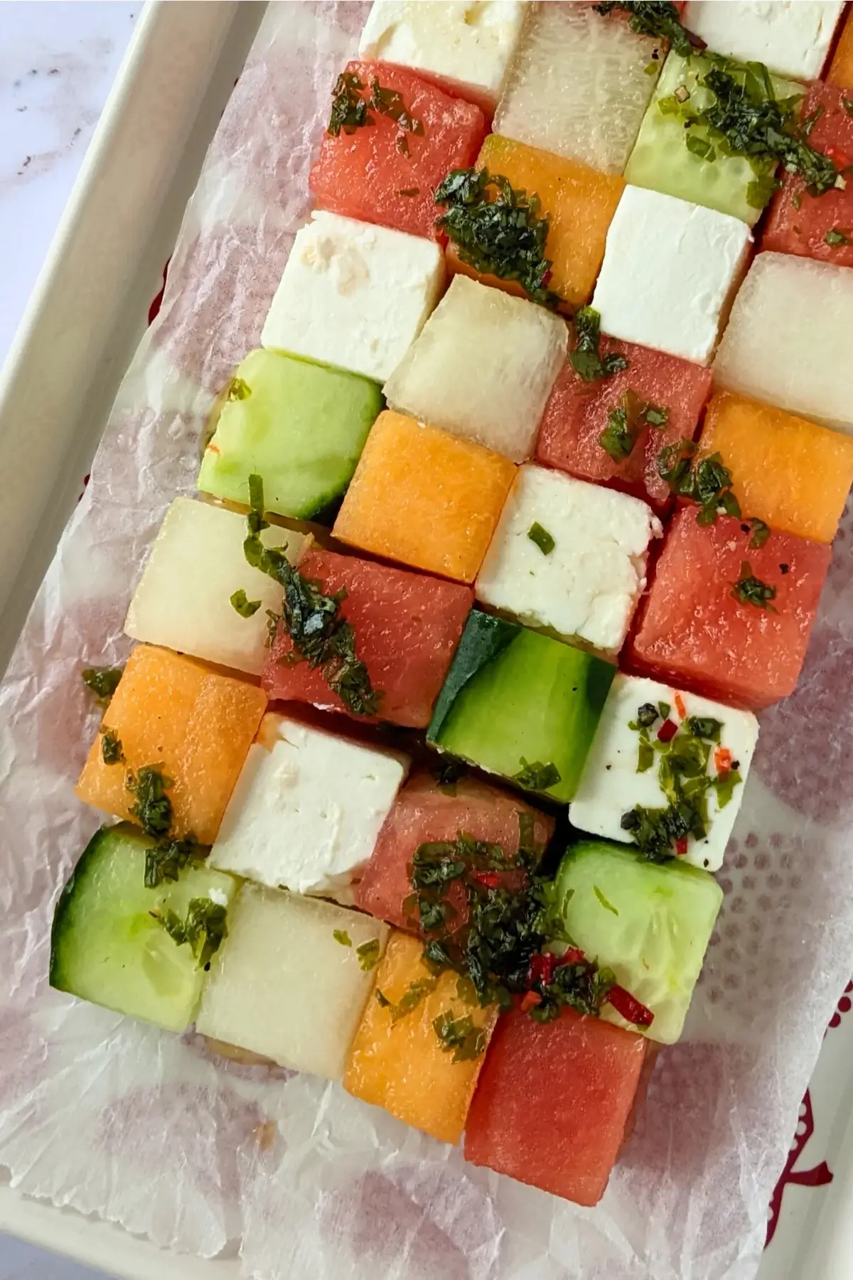 Cubed melon, cucumber, watermelon & feta Tetris salad arranged in a grid with a drizzle of vinaigrette.