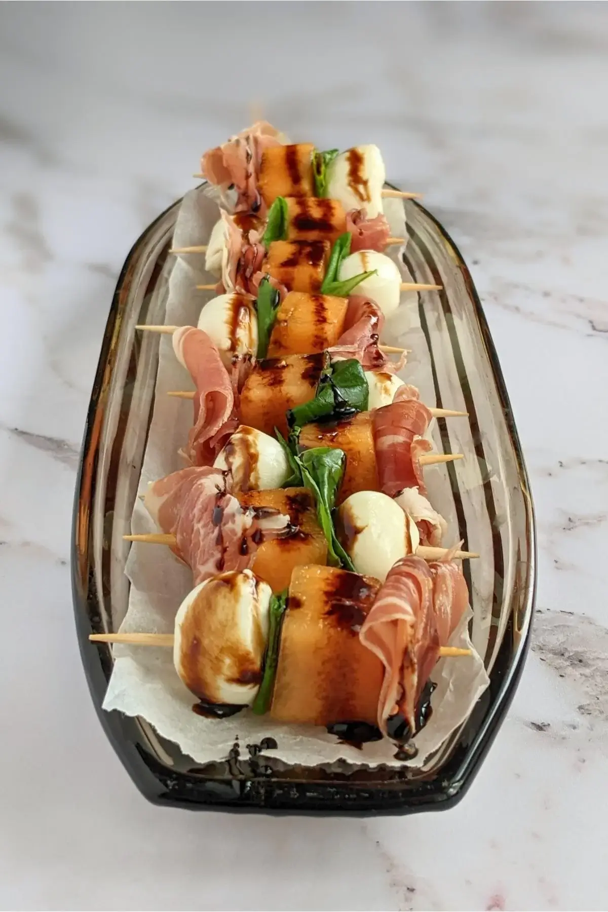 Skewers with sweet melon, salty prosciutto, and creamy mozzarella, finished with basil and balsamic drizzle.