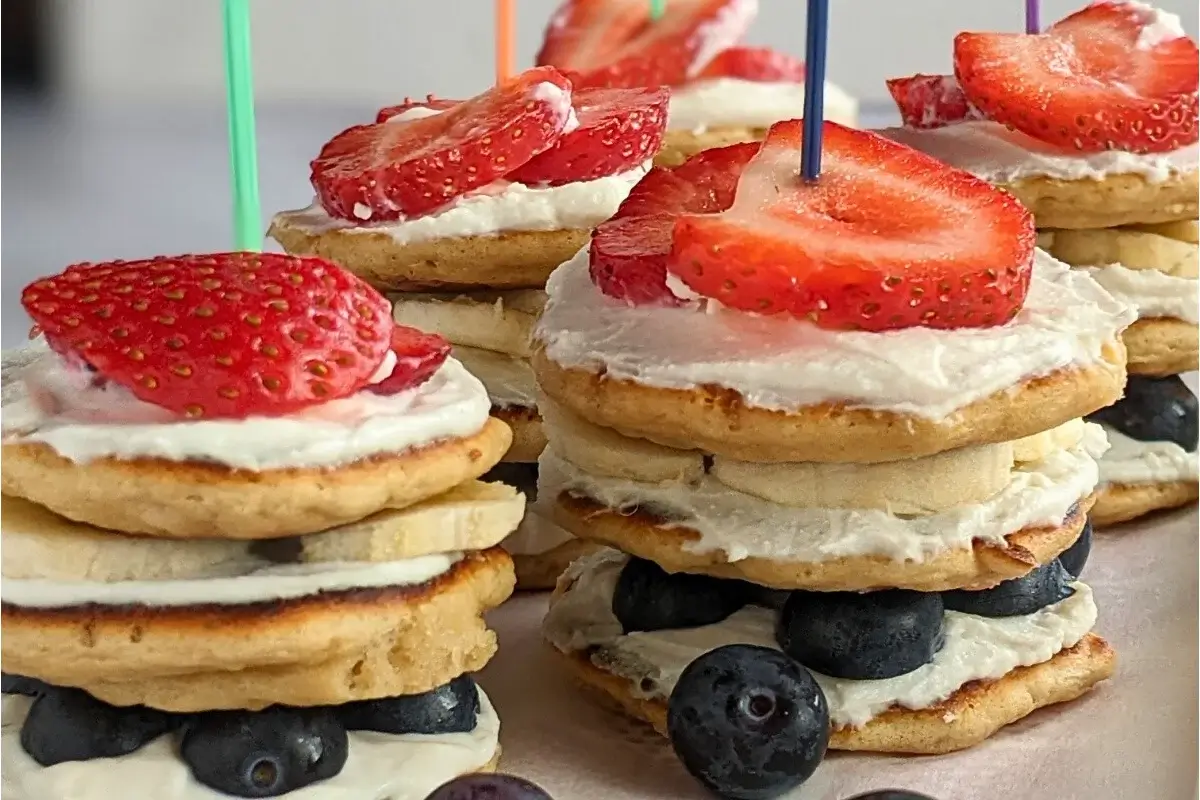Mini pancake stacks layered with berries, banana and ricotta cream, perfect for a fun and easy brunch or dessert.
