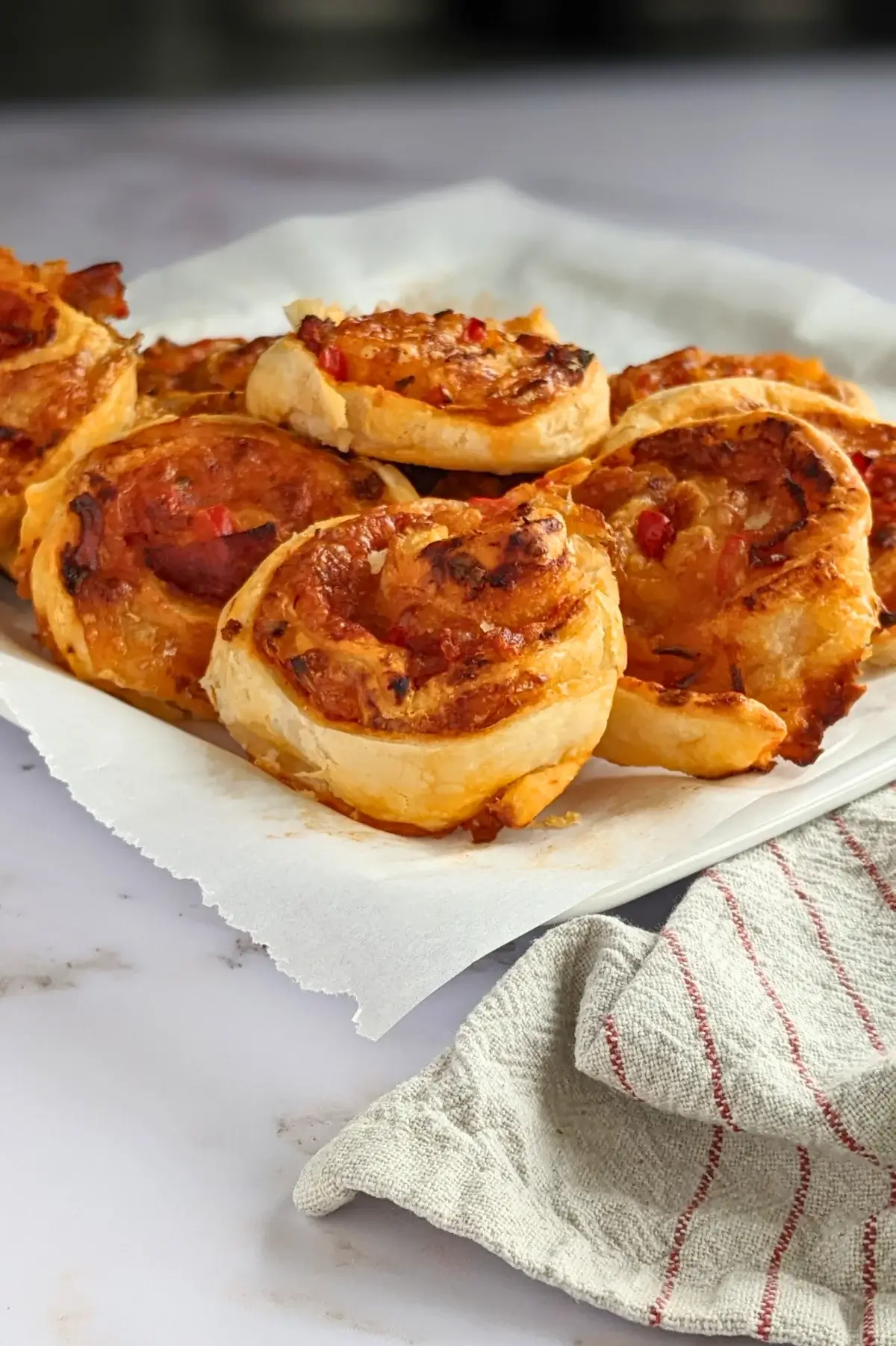 Golden brown pizza pinwheels filled with tomato sauce, salami, and melted cheese.