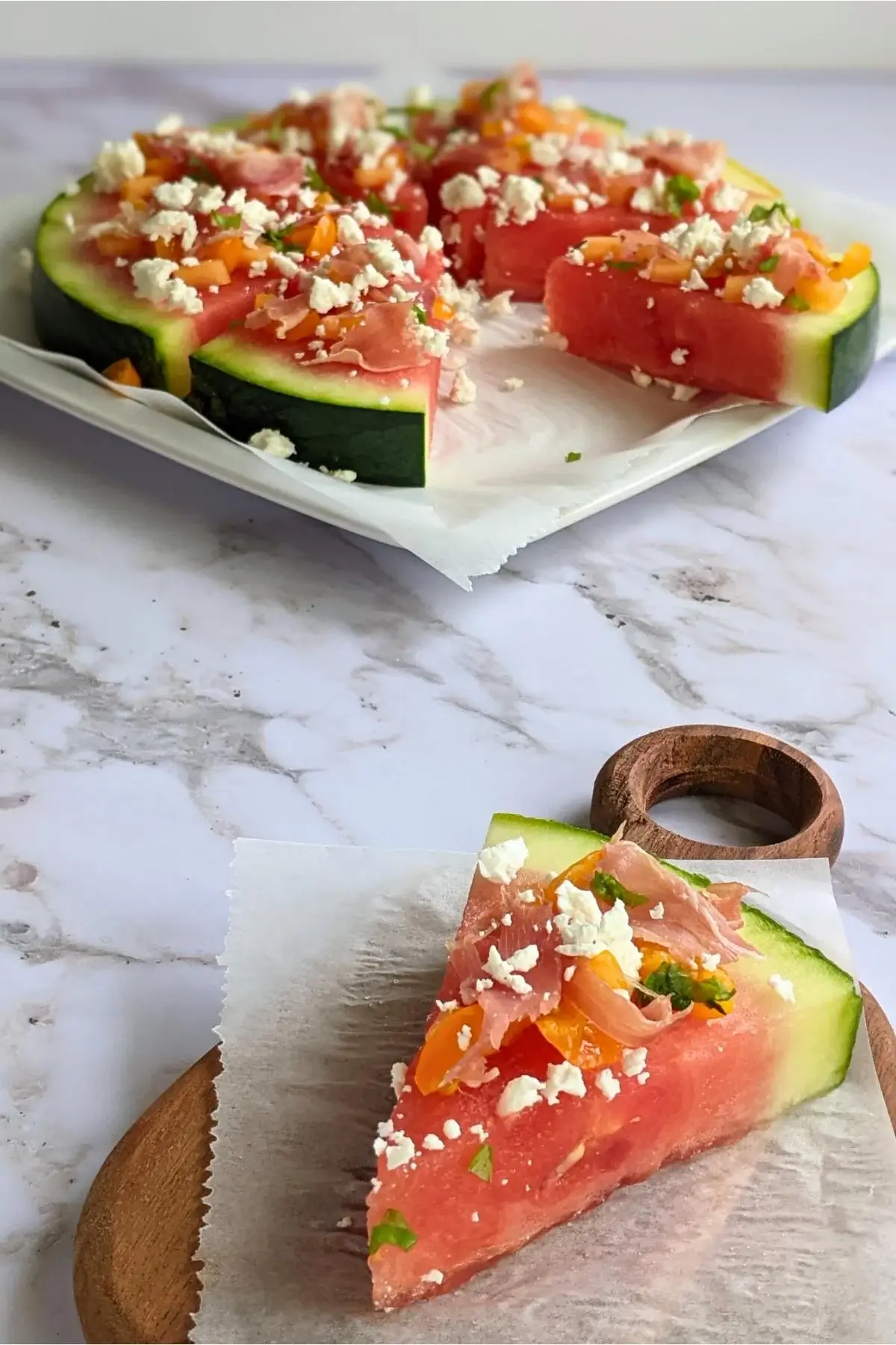 Watermelon slice topped like a pizza with melon slices, prosciutto, and feta.