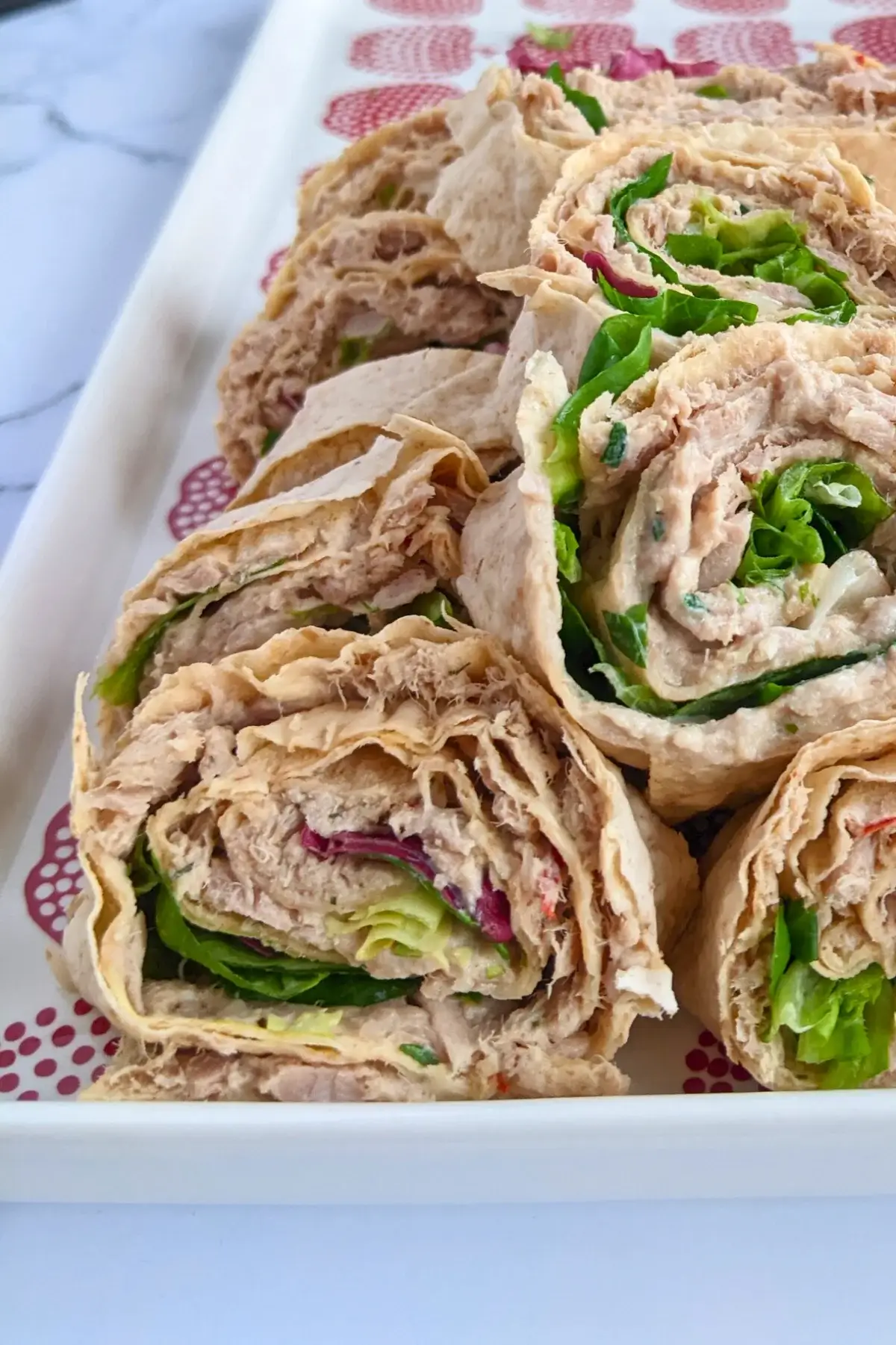 Smoked salmon flatbread rolls sliced into pinwheels filled with salmon-cream cheese spread and fresh greens.
