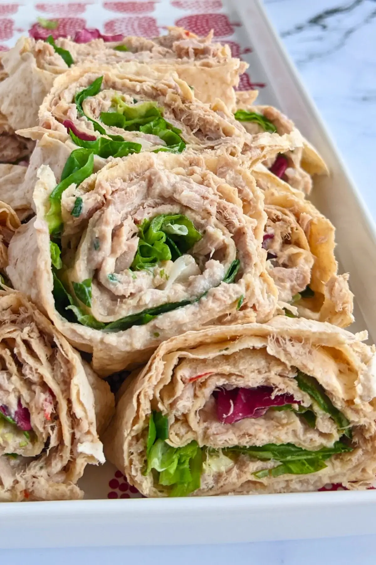 Rolled flatbread slices filled with salmon-cream cheese spread and fresh greens.