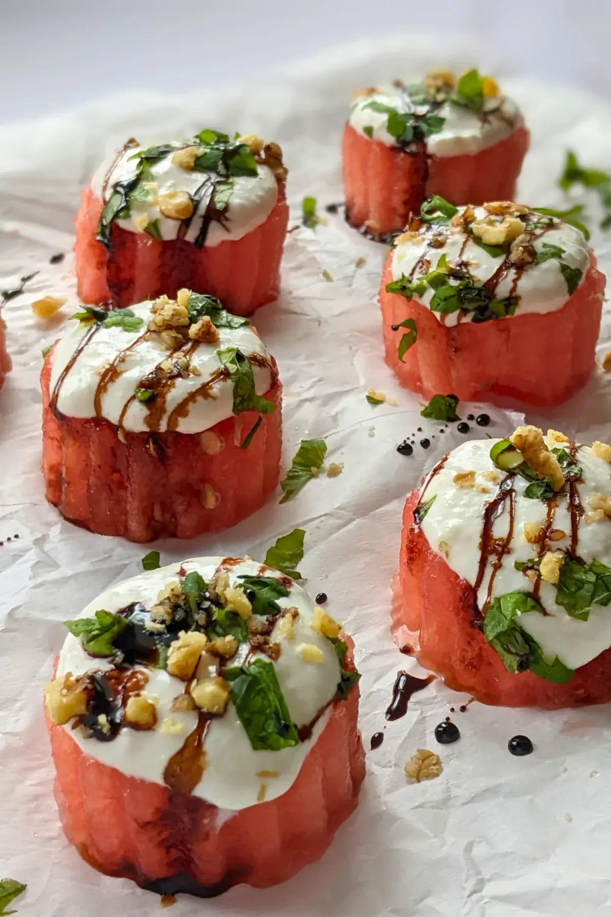 Watermelon & goat’s cheese appetizers topped with mint, walnuts, and balsamic glaze for a sweet-savory bite.