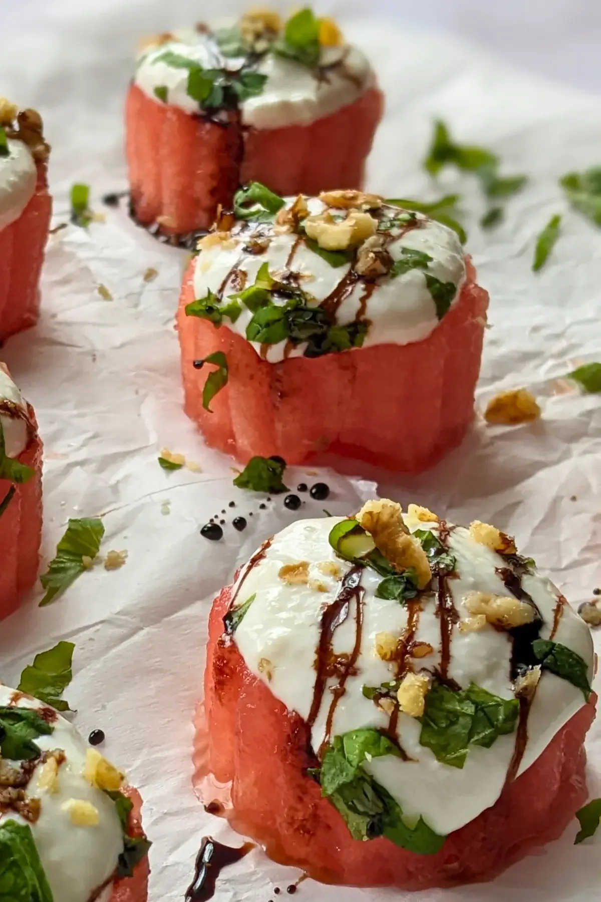 Watermelon and goat’s cheese appetizers topped with mint, balsamic glaze, and walnuts.