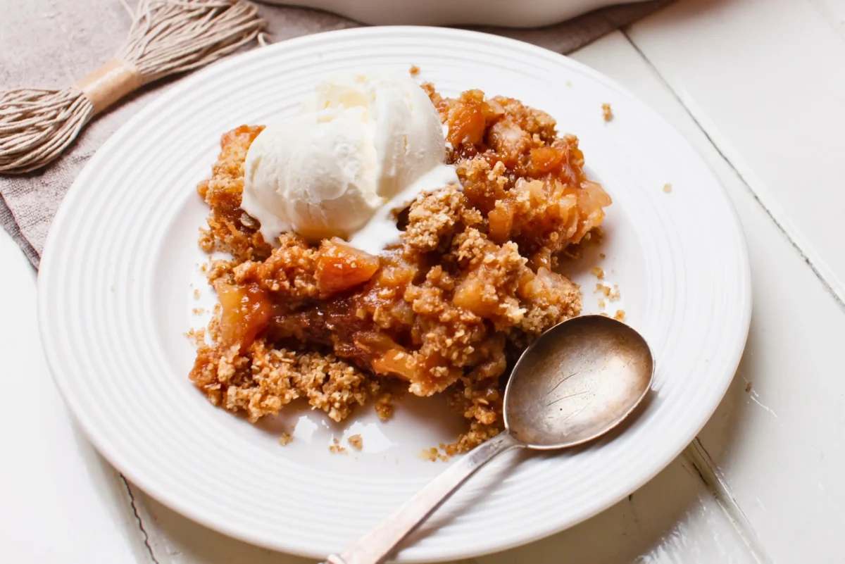 Fruit-filled crumble with a golden, crumbly topping and chunks of rhubarb and apple at the bottom.