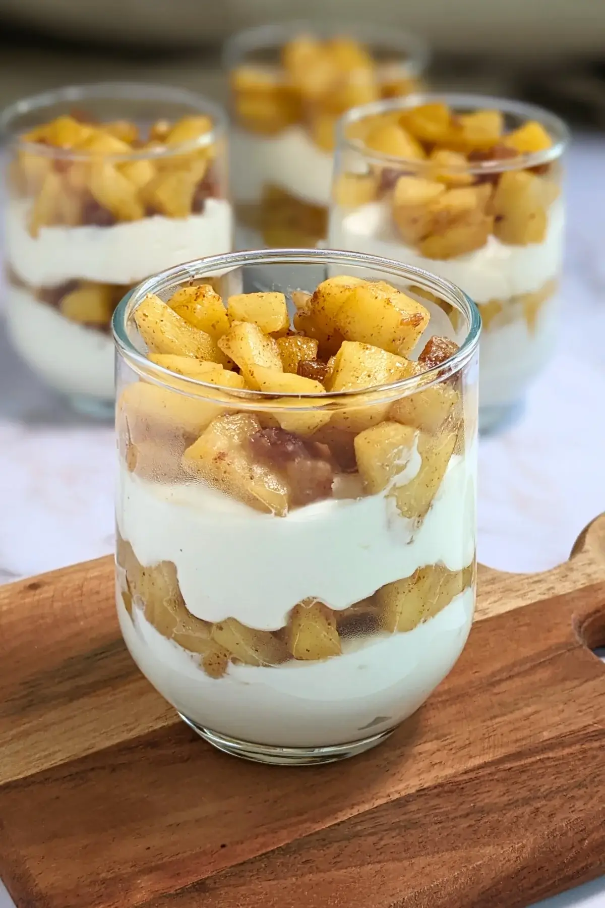 Healthy layered apple parfait dessert with whipped ricotta and cream, topped with stewed apples and chopped dates.