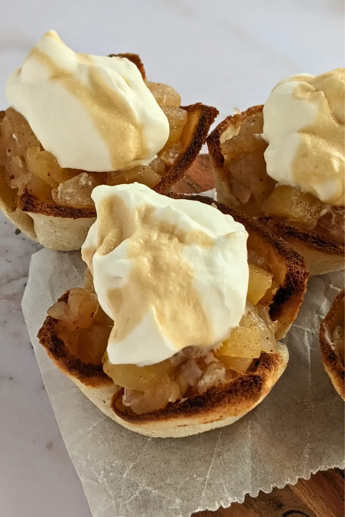 Toasted bread cups filled with applesauce and topped with swirls of whipped cream.