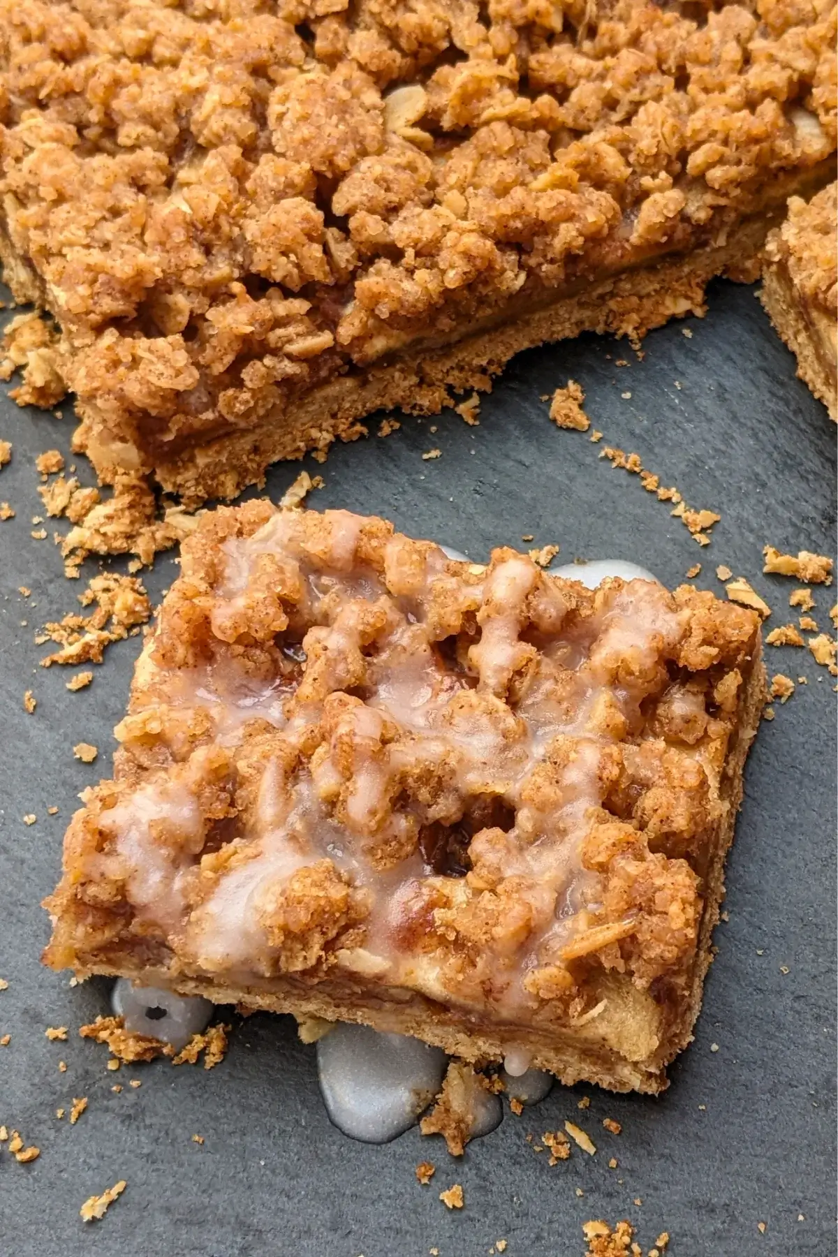 Apple crisp bars made with a flour and oat base, cinnamon apple filling, and streusel topping, drizzled with an icing sugar and milk frosting.