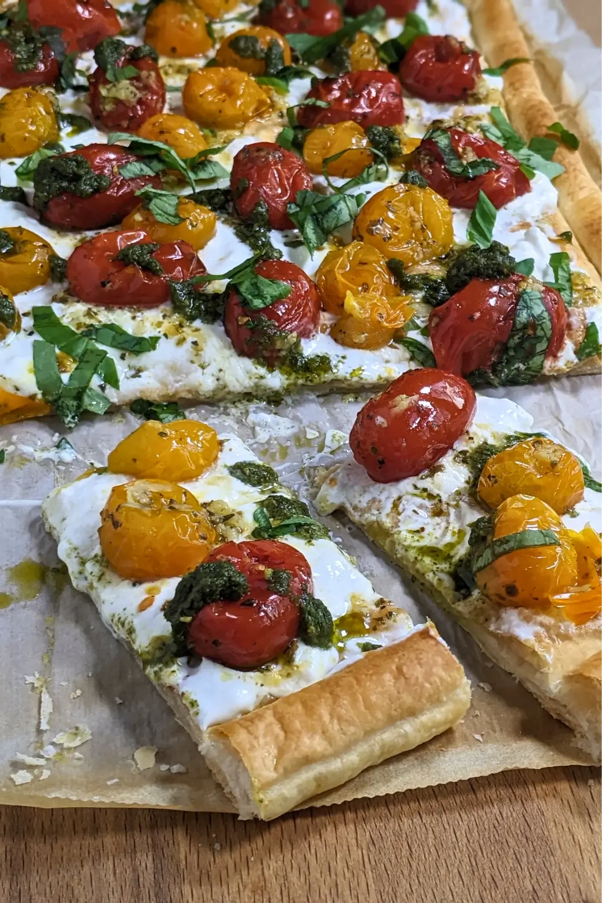 Cherry tomato and burrata appetizer with puff pastry, pesto, and fresh shredded basil.