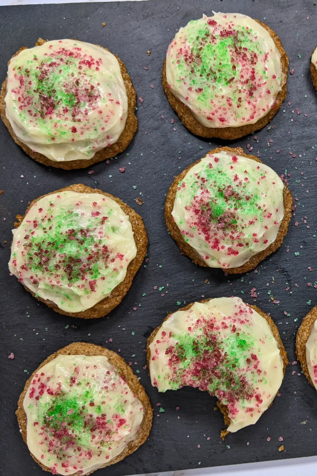 Christmas pumpkin sugar cookies made with healthier wholemeal flour and coconut sugar, frosted with a classic butter and cream cheese icing, and decorated with red and green sugar sprinkles.
