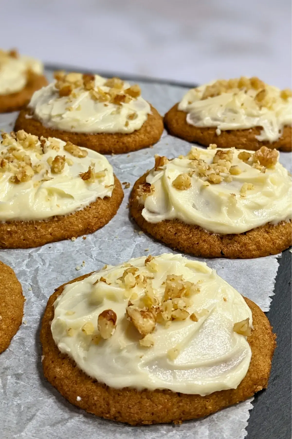 Pumpkin cookies with cream cheese icing made partly with healthier wholemeal flour and coconut sugar, frosted with a cream cheese icing and topped with crushed walnuts for decoration.