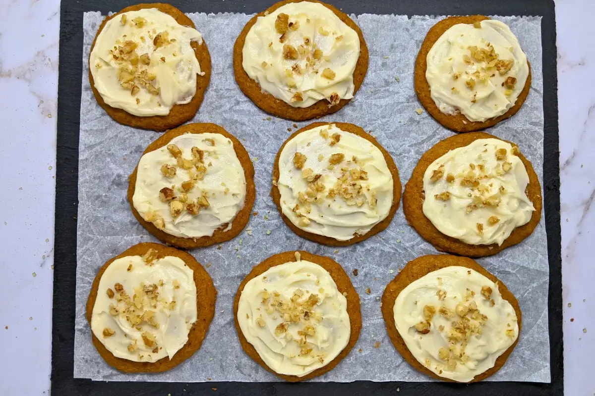 Pumpkin cookies with cream cheese icing made partly with healthier wholemeal flour and coconut sugar, frosted with a cream cheese icing and topped with crushed walnuts for decoration.