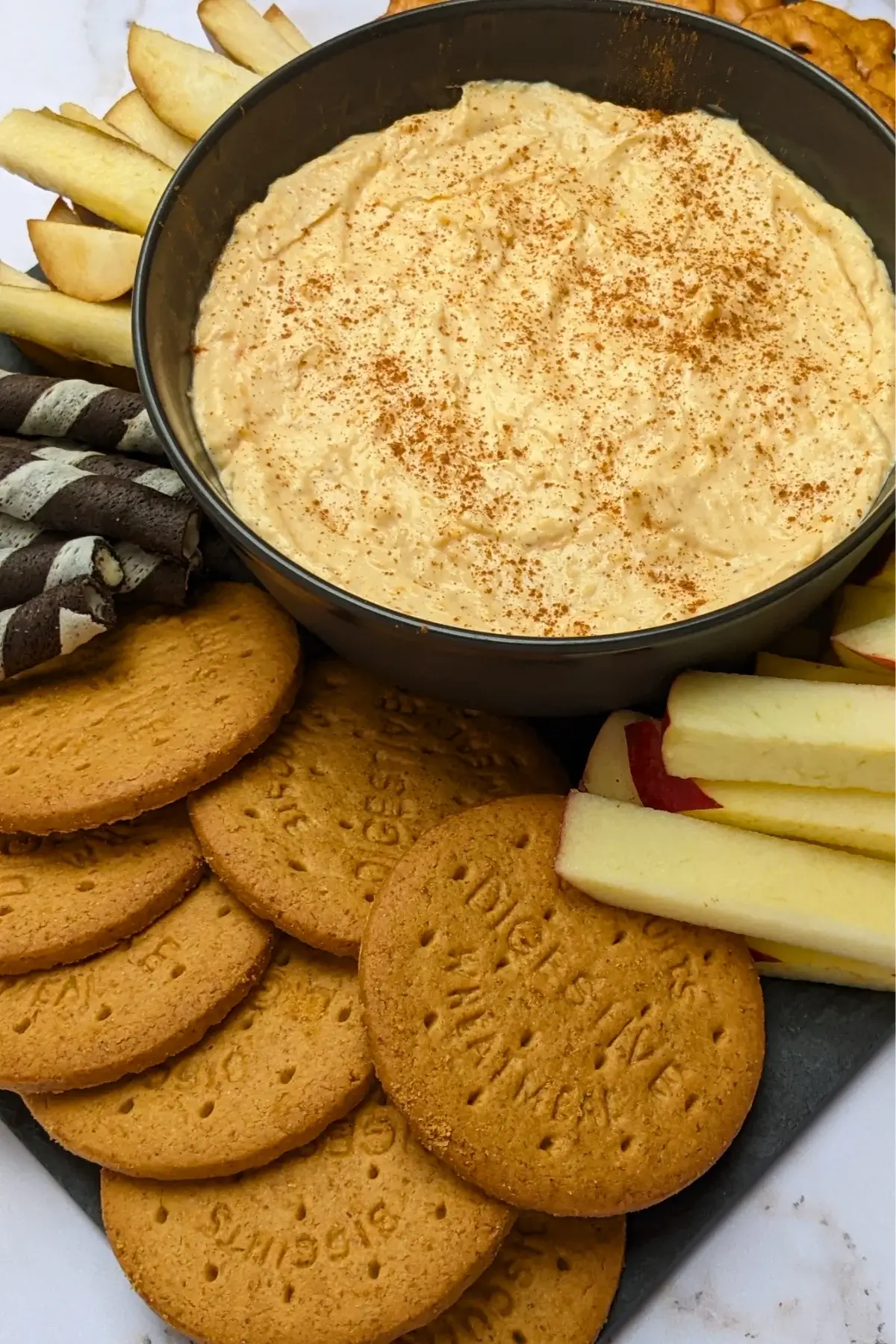 Pumpkin dip with cream cheese, cinnamon, pumpkin pie spice and Greek yogurt served with sliced apples and pears, vanilla wafer sticks, biscuits, and pretzels.