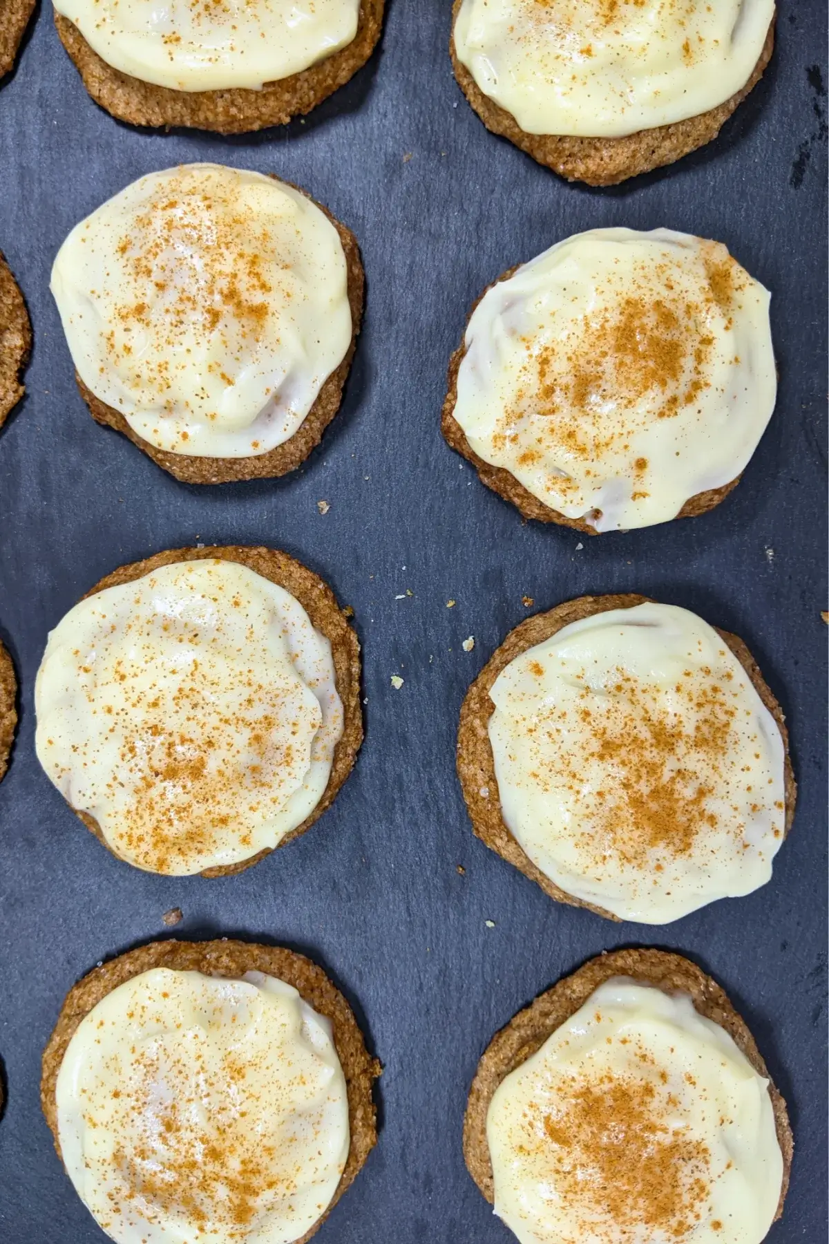 Pumpkin sugar cookies made with healthier wholemeal flour and coconut sugar, frosted with a classic cream cheese icing, and decorated with sprinkles of cinnamon.