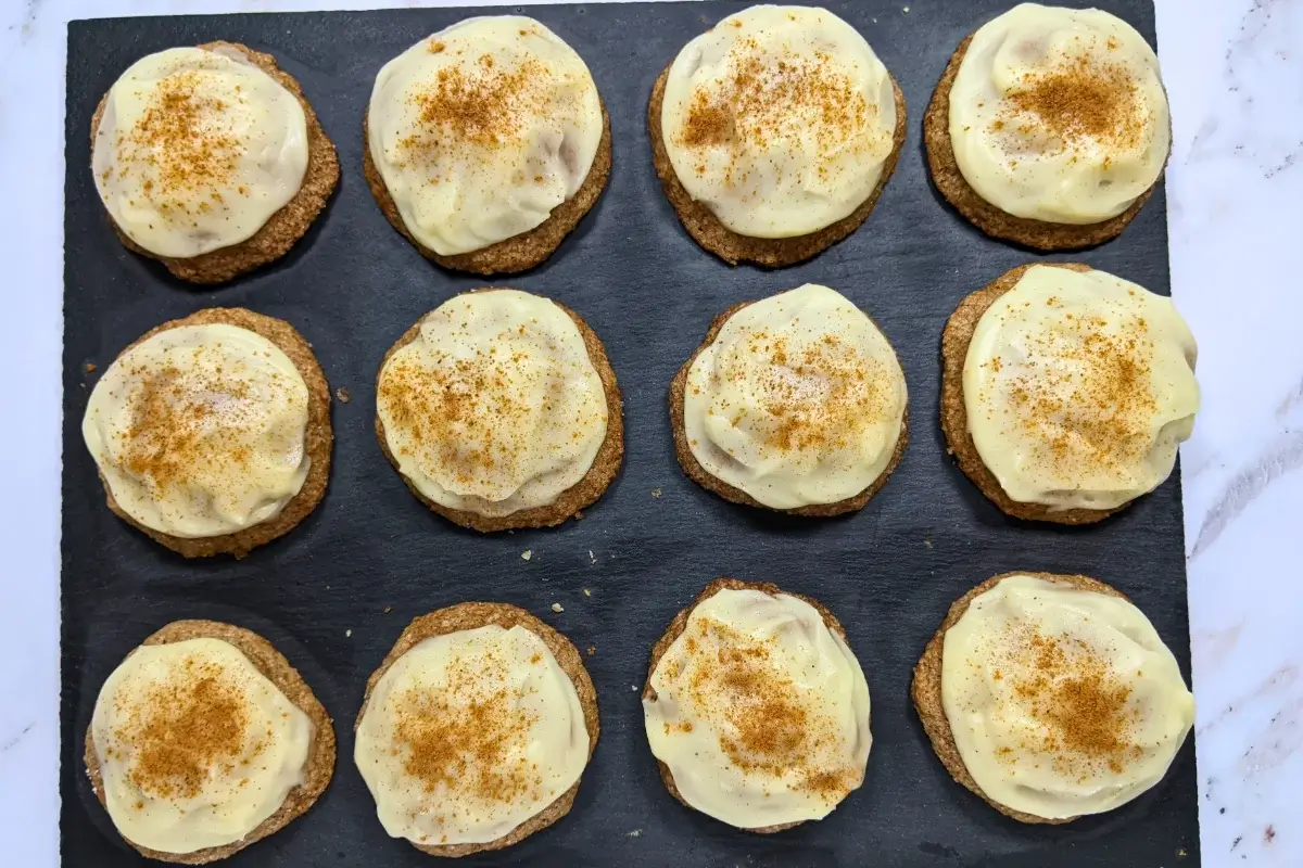 Pumpkin sugar cookies made with healthier wholemeal flour and coconut sugar, frosted with a classic cream cheese icing, and decorated with sprinkles of cinnamon.