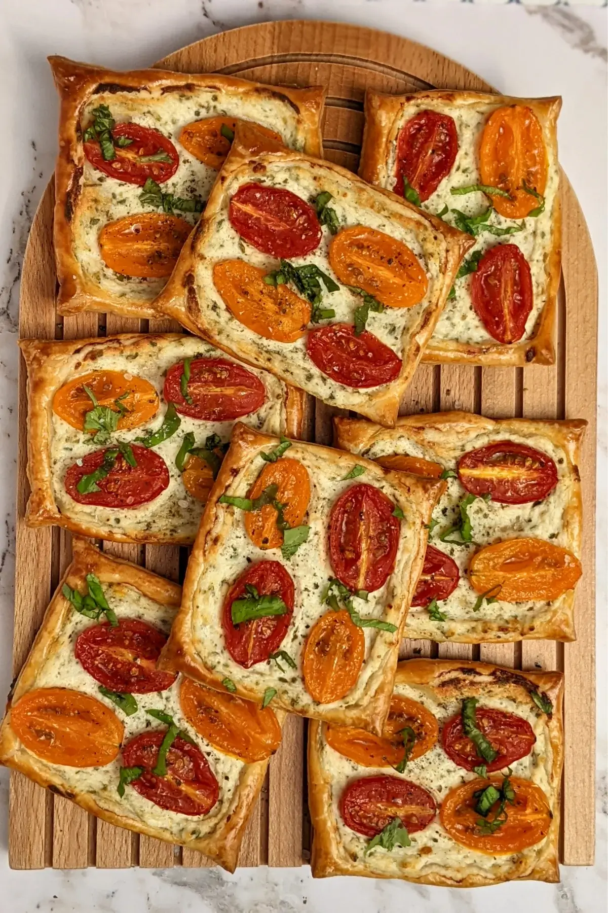 Roasted cherry tomato tarts with puff pastry - a puff pastry appetizer filled with ricotta and parmesan and topped with red and yellow cherry tomatoes and basil.