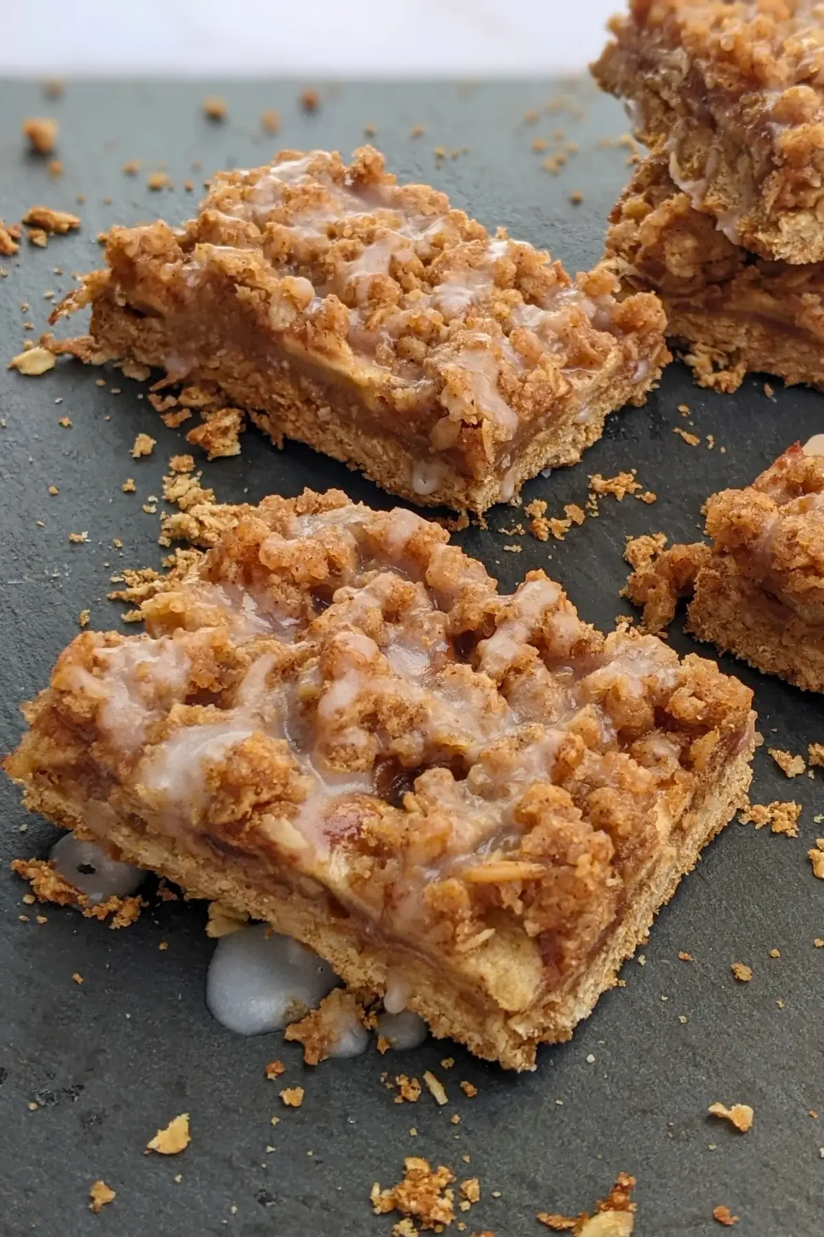 Apple crisp bars made with a flour and oat base, cinnamon apple filling, and streusel topping, drizzled with an icing sugar and milk frosting.