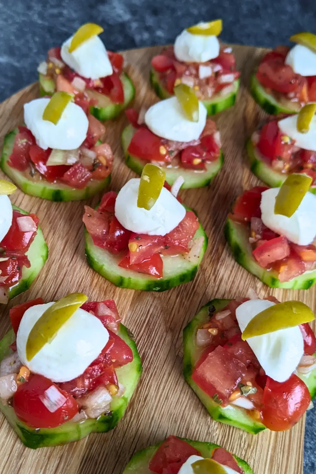 Fresh bruschetta cucumber bites topped with mozzarella balls and sliced olives for decoration.