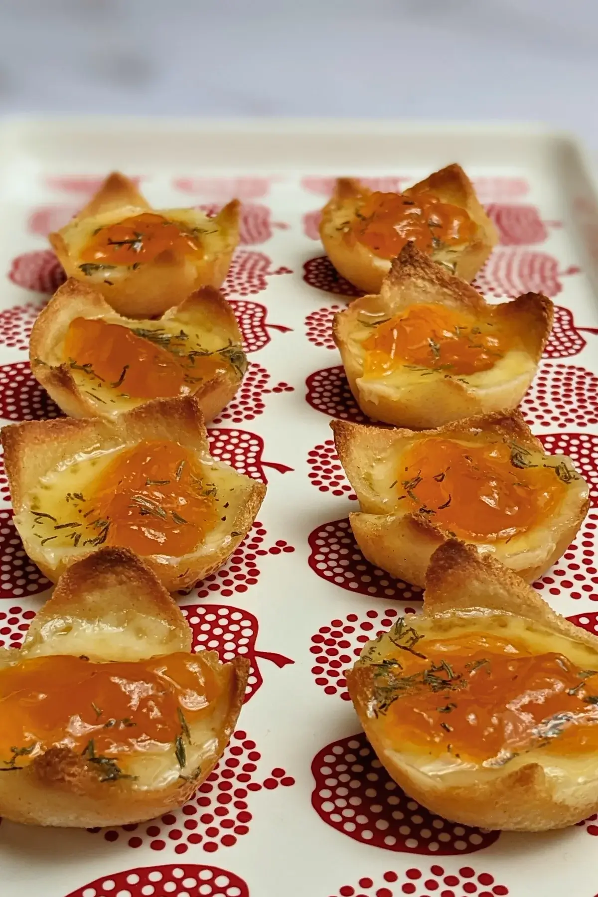 Cheddar cheese and apricot jam appetizer bites - mini bread toast cups filled with cheddar cheese, topped with apricot jam and a honey-dryed thyme drizzle.
