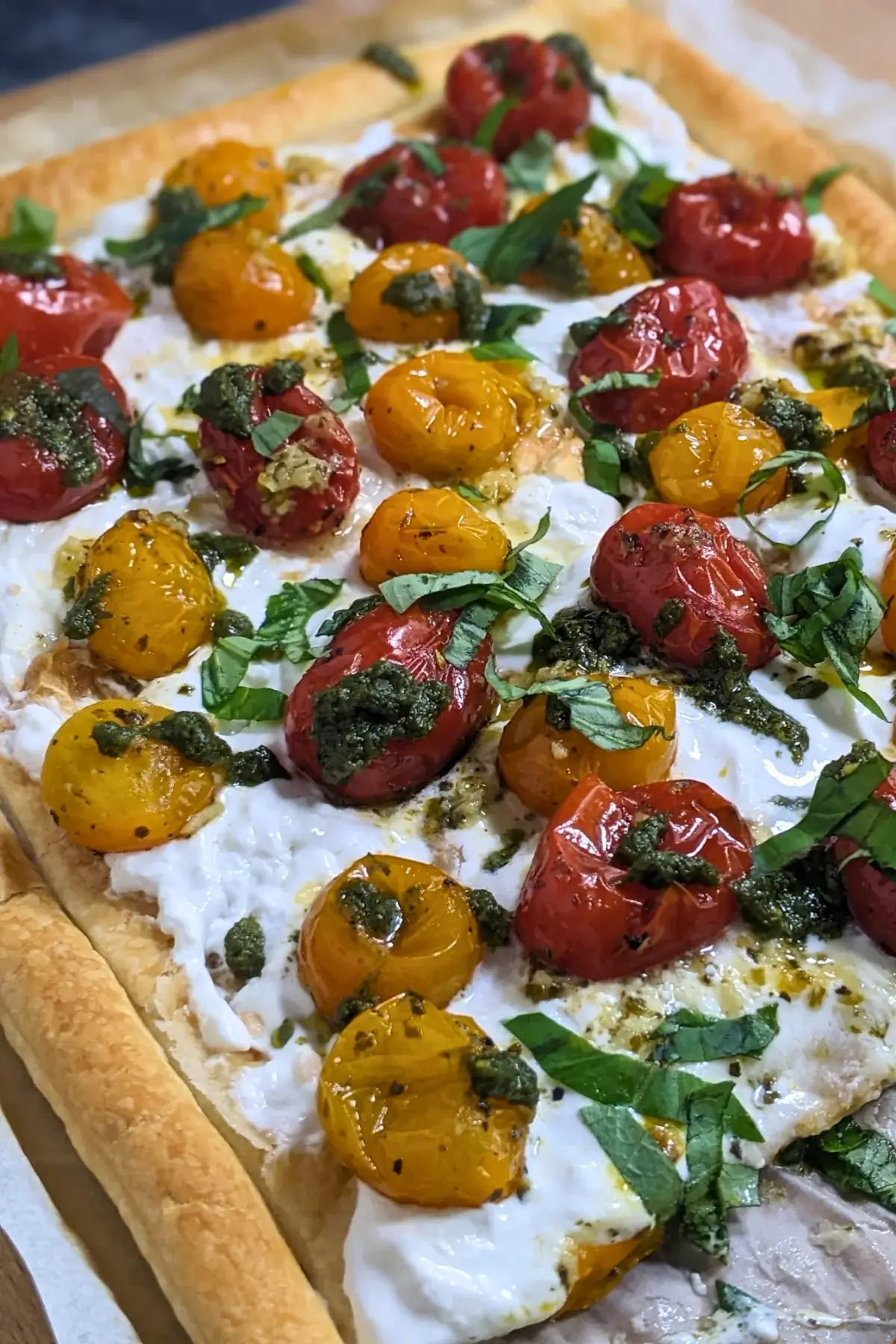 Cherry tomato and burrata appetizer with puff pastry, pesto, and fresh shredded basil.