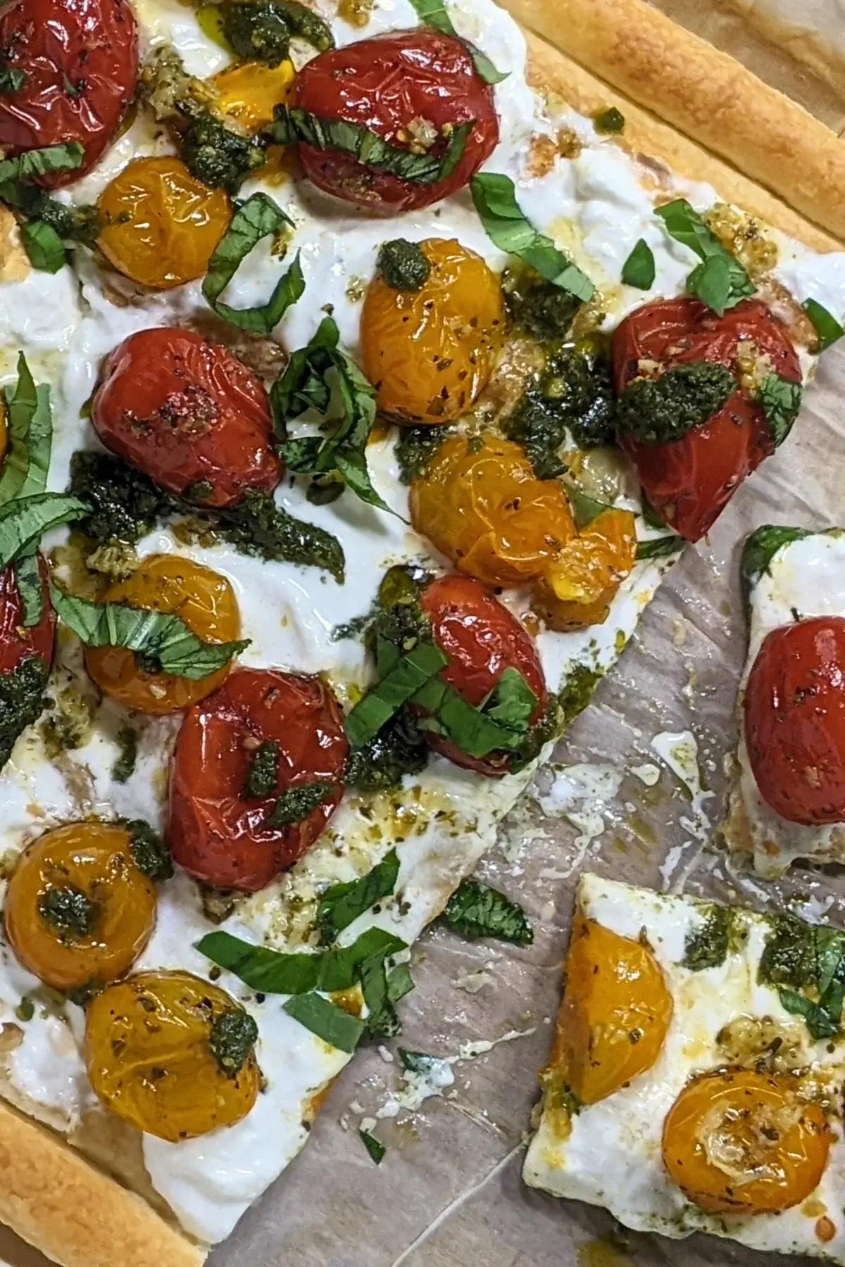 Cherry tomato and burrata appetizer with puff pastry, pesto, and fresh shredded basil.