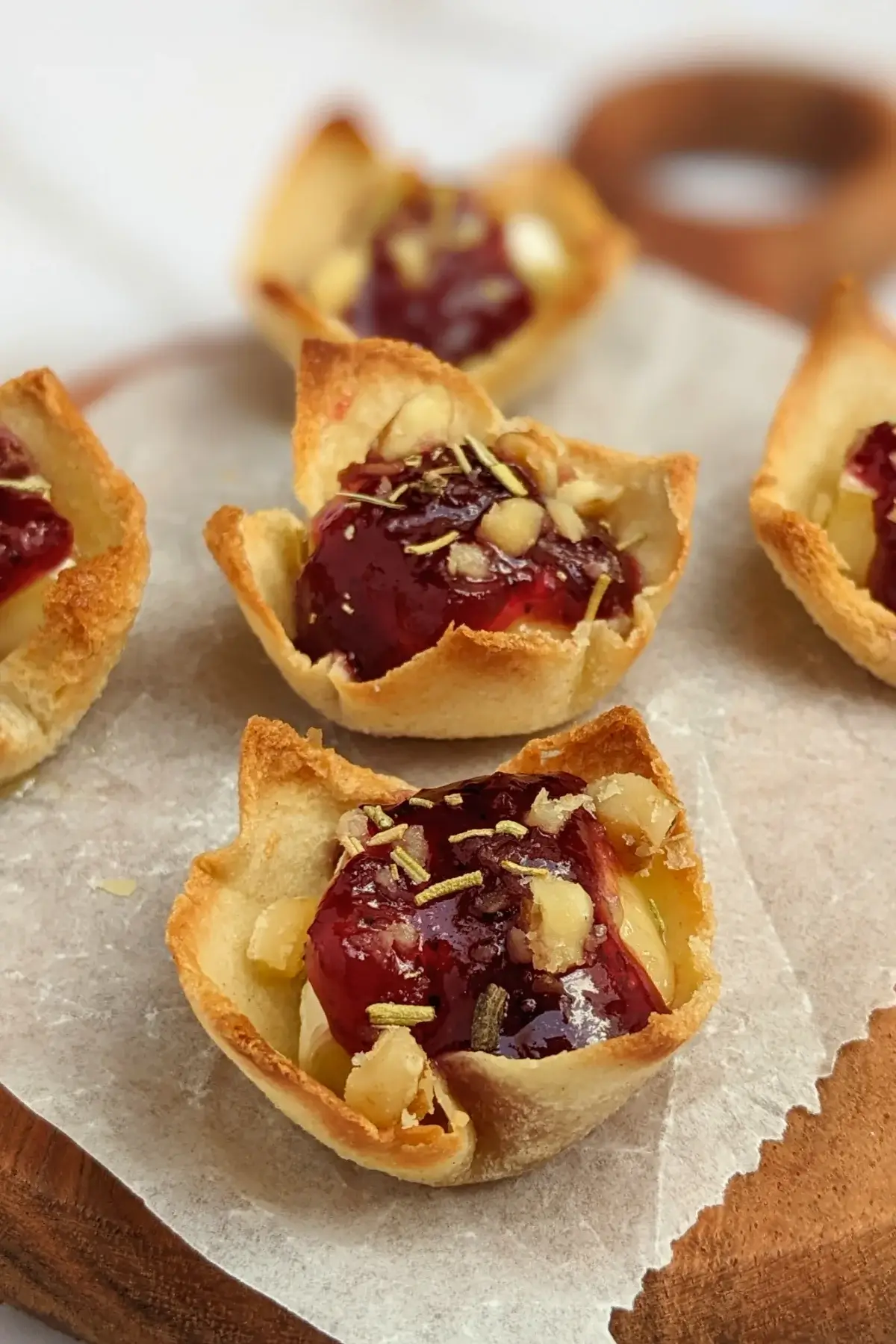 Cranberry brie bites - mini toast cup appetizers filled with brie cheese, topped with cranberry jam and crushed walnuts.