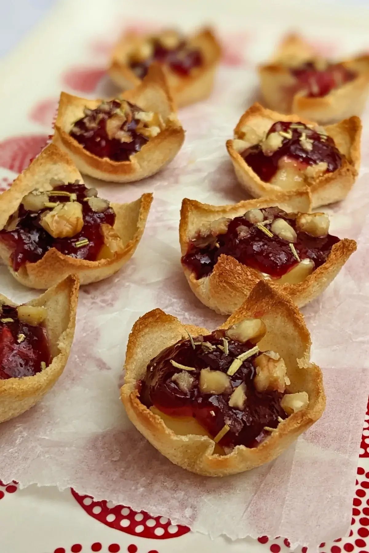 Cranberry brie bites - mini toast cup appetizers filled with brie cheese, topped with cranberry jam and crushed walnuts