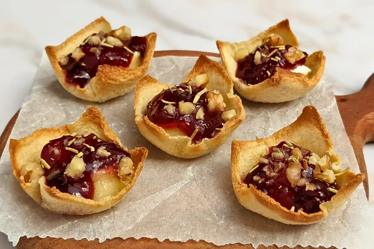 Cranberry brie bites - mini toast cup appetizers filled with brie cheese, topped with cranberry jam and crushed walnuts